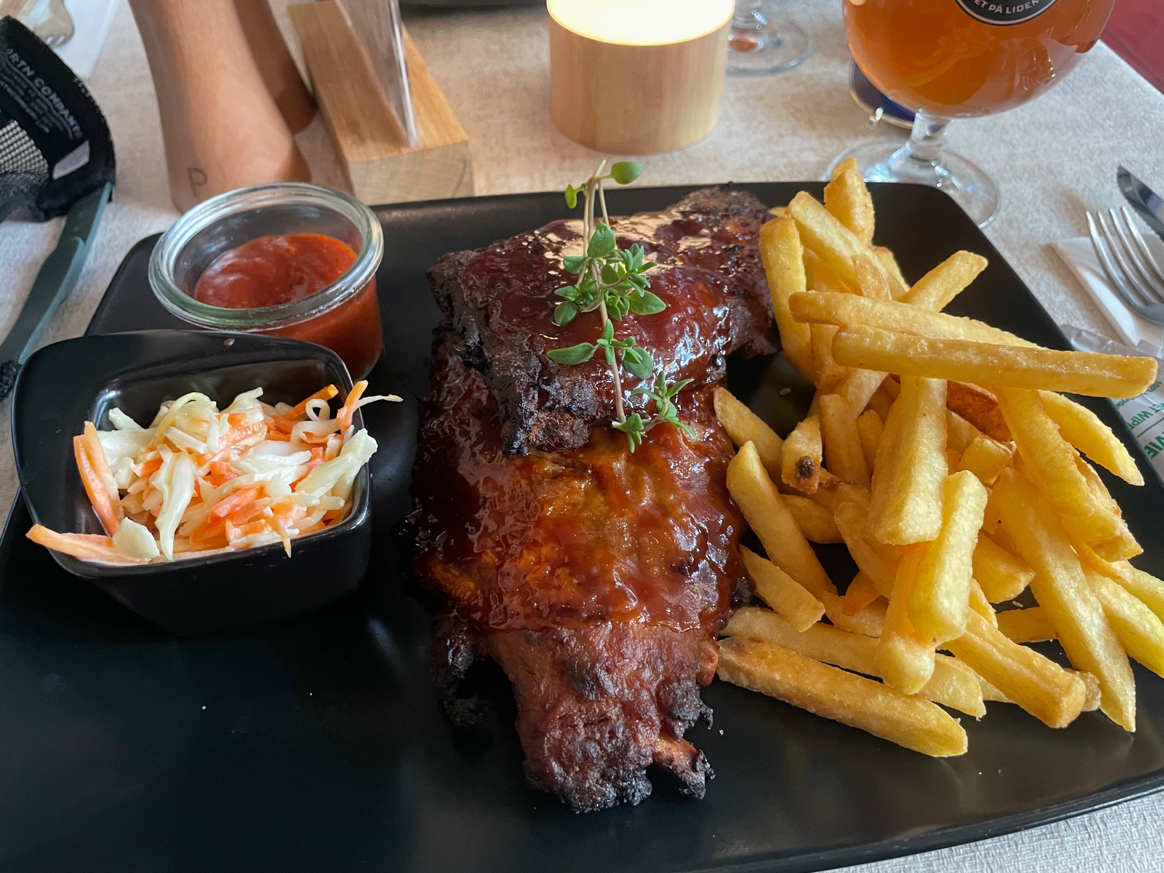Jensens Bøfhus Kolding review spare ribs meal served with fries, coleslaw, barbecue sauce, garnish, and a drink on the table at the former Kolding Storcenter restaurant