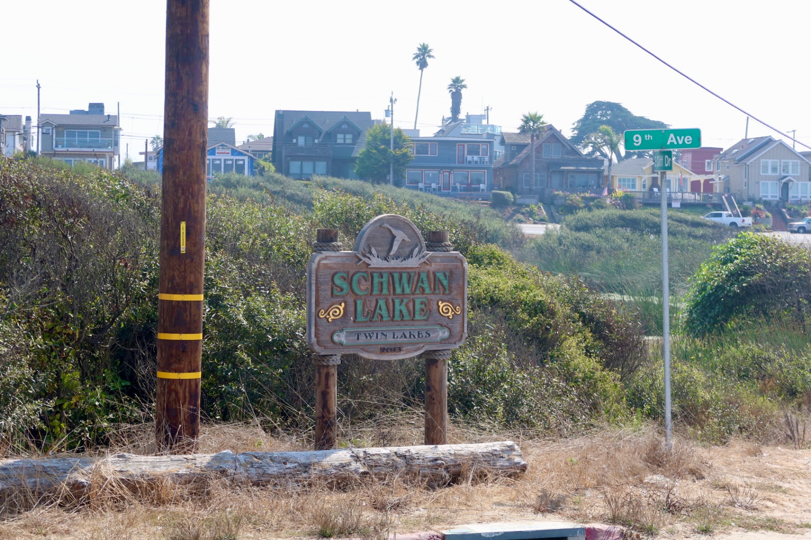 Schwan Lake Twin Lakes sign near Twin Lakes State Beach in Santa Cruz, California with coastal homes in the background