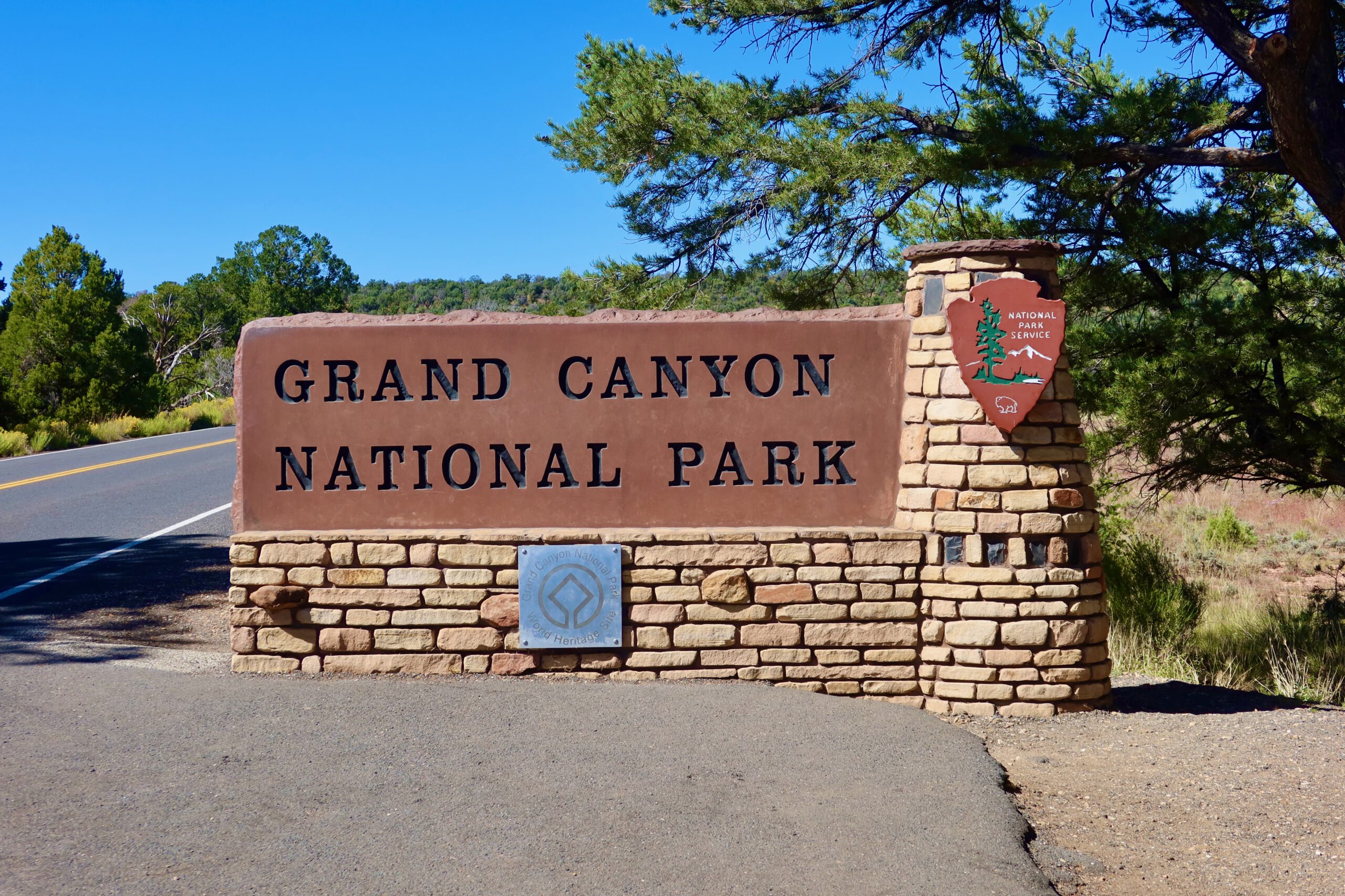 Grand Canyon National Park entrance sign along the road under a clear blue sky