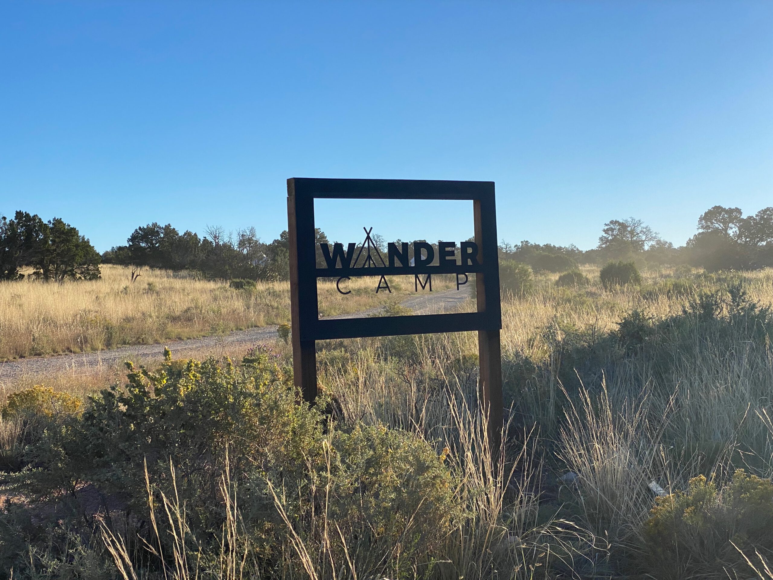 Wander Camp Grand Canyon entrance sign at sunrise in the Arizona high desert, marking a rustic glamping stay near Grand Canyon National Park