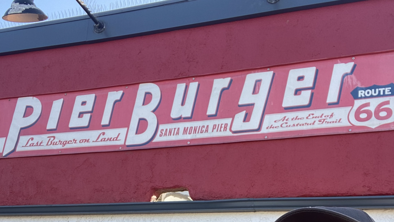 PierBurger sign on Santa Monica Pier, California, with red diner-style branding, Route 66 reference, and oceanfront location at the end of the pier