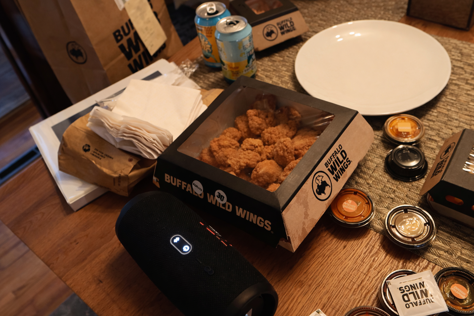 Buffalo Wild Wings Uber Eats delivery in Boise with boneless wings, fries, multiple sauces and drinks on a wooden table