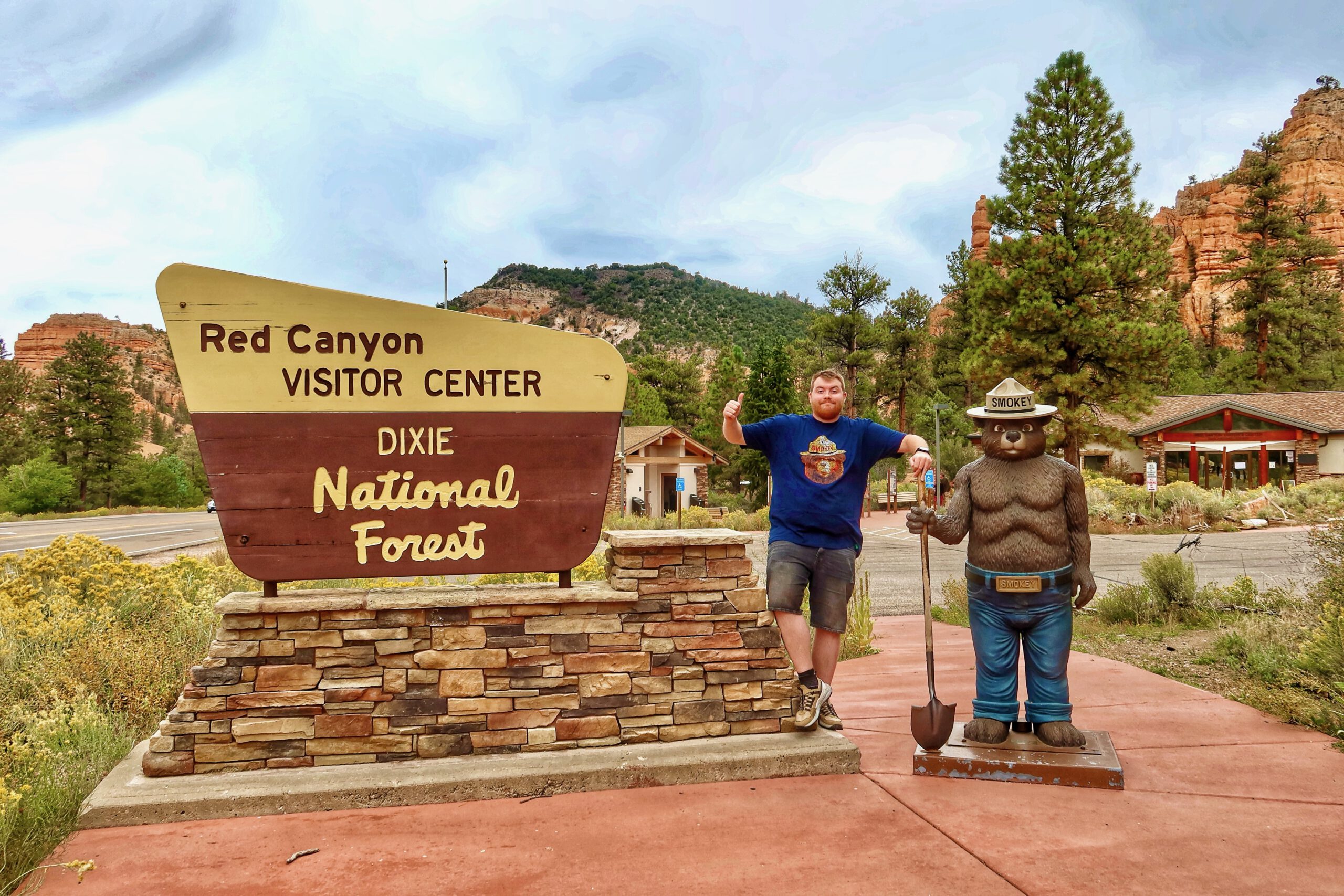 Timo van den Berg, also known as Timeuw, standing next to Smokey Bear at the Red Canyon Visitor Center in Dixie National Forest, Utah, during a road trip between Bryce Canyon and Zion