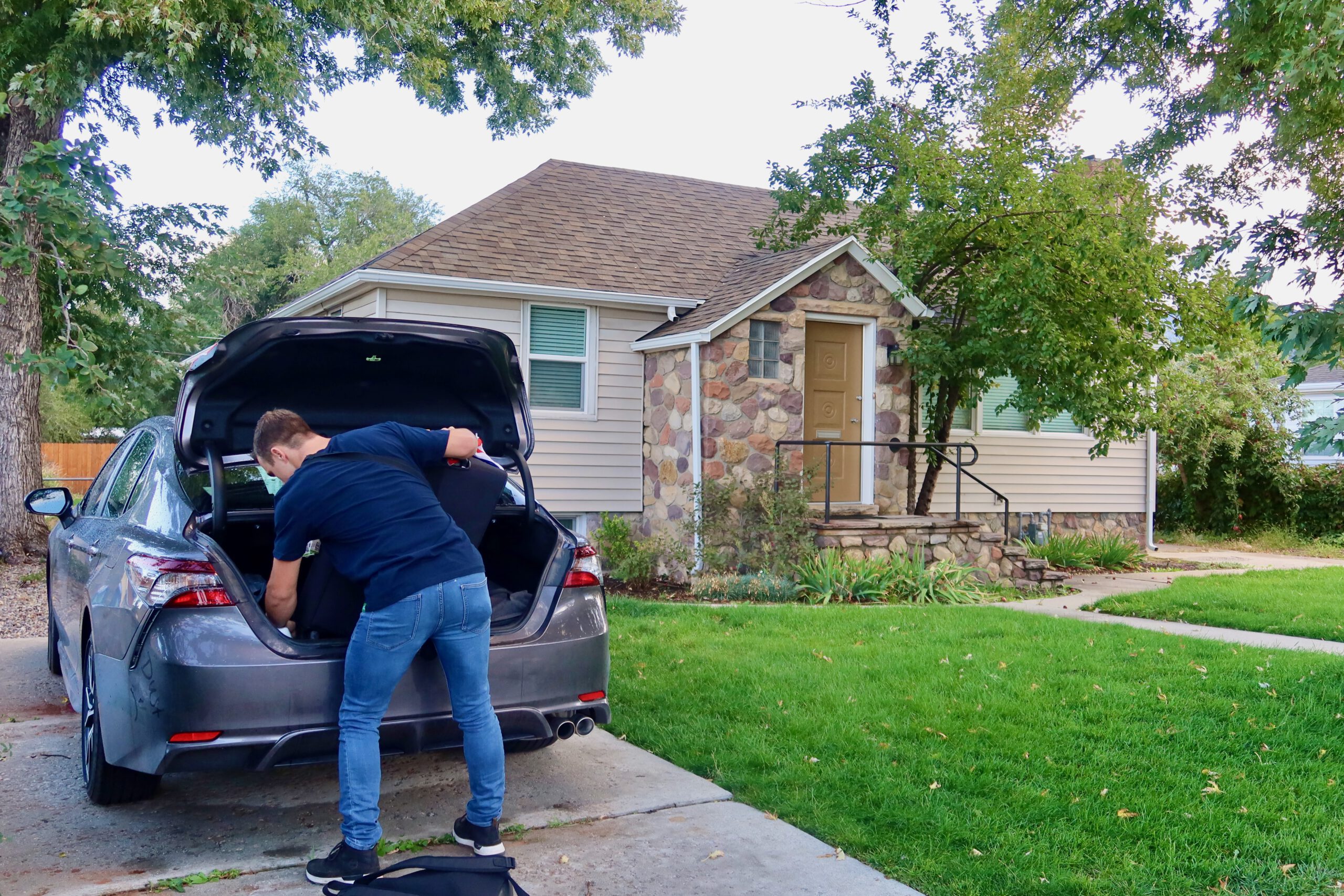 Guest unloading luggage from a car at a Sandy Utah Airbnb, showing free on site parking in front of a quiet residential home, ideal for a comfortable Utah road trip stop