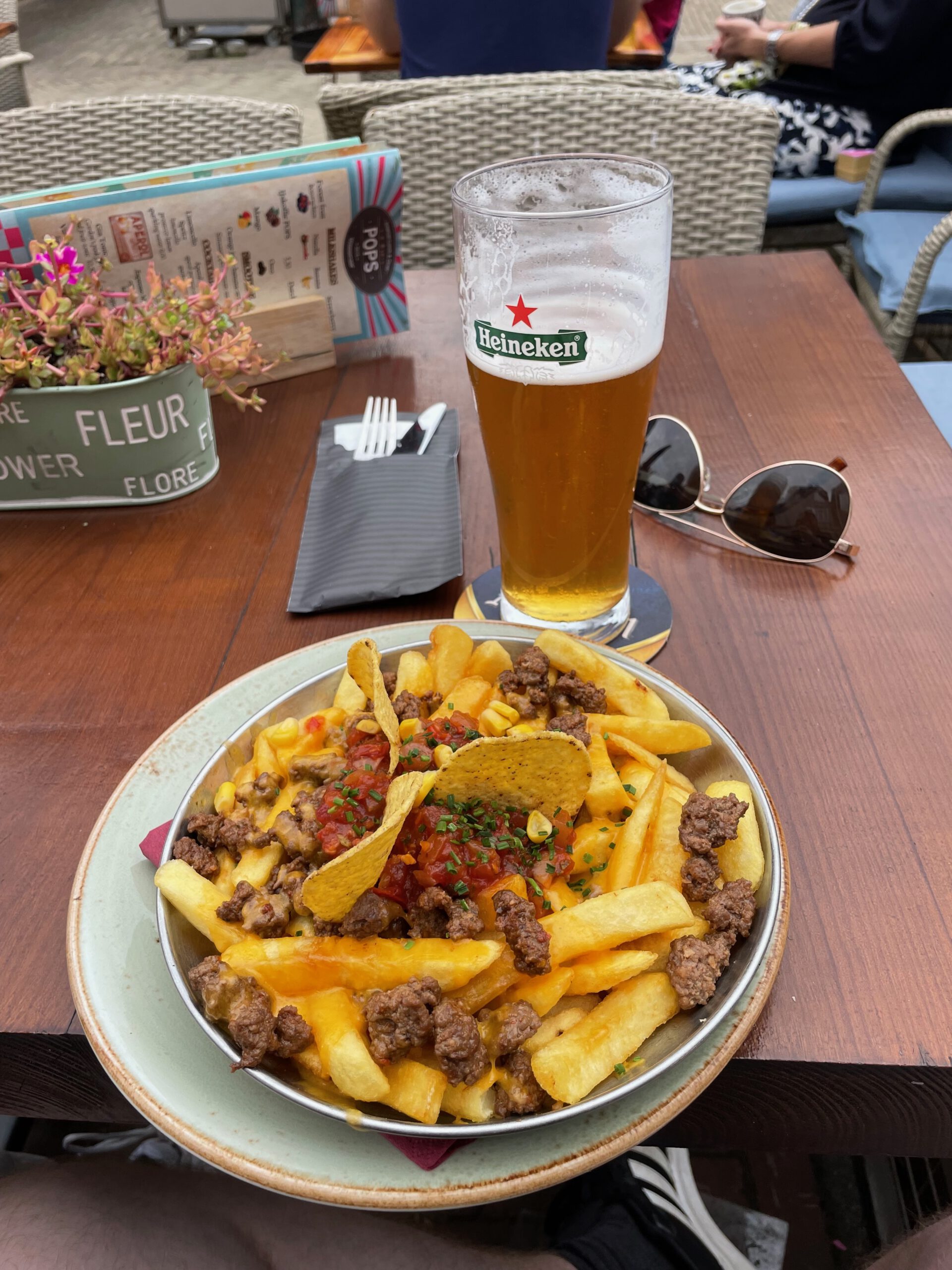 Loaded fries with cheddar cheese, seasoned beef and tortilla chips at POPS Wassenaar, served with a cold beer on the terrace