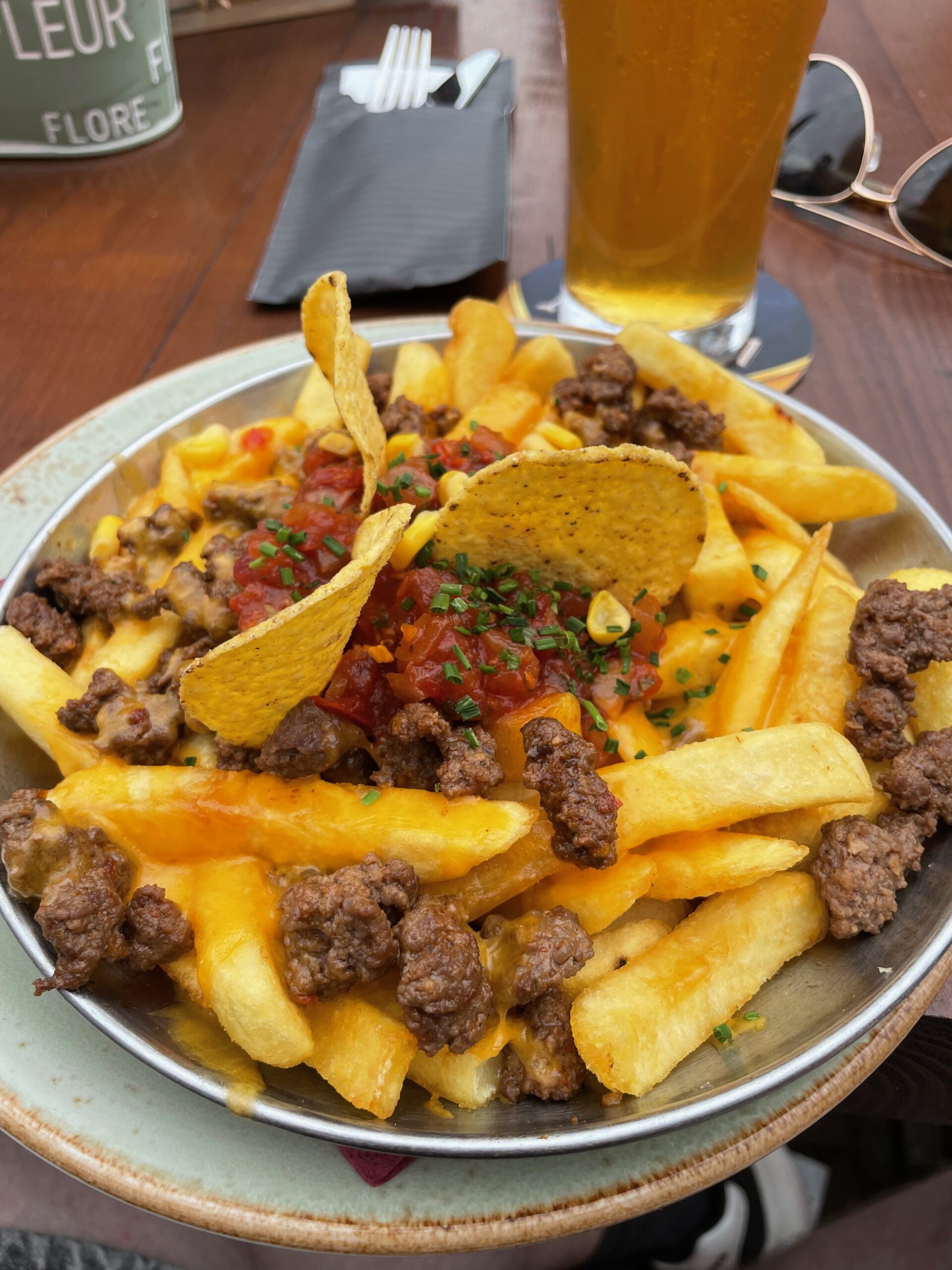 POPS Wassenaar loaded fries with melted cheese, seasoned beef, tortilla chips and chives, served with a cold beer at POPS Wassenaar American diner