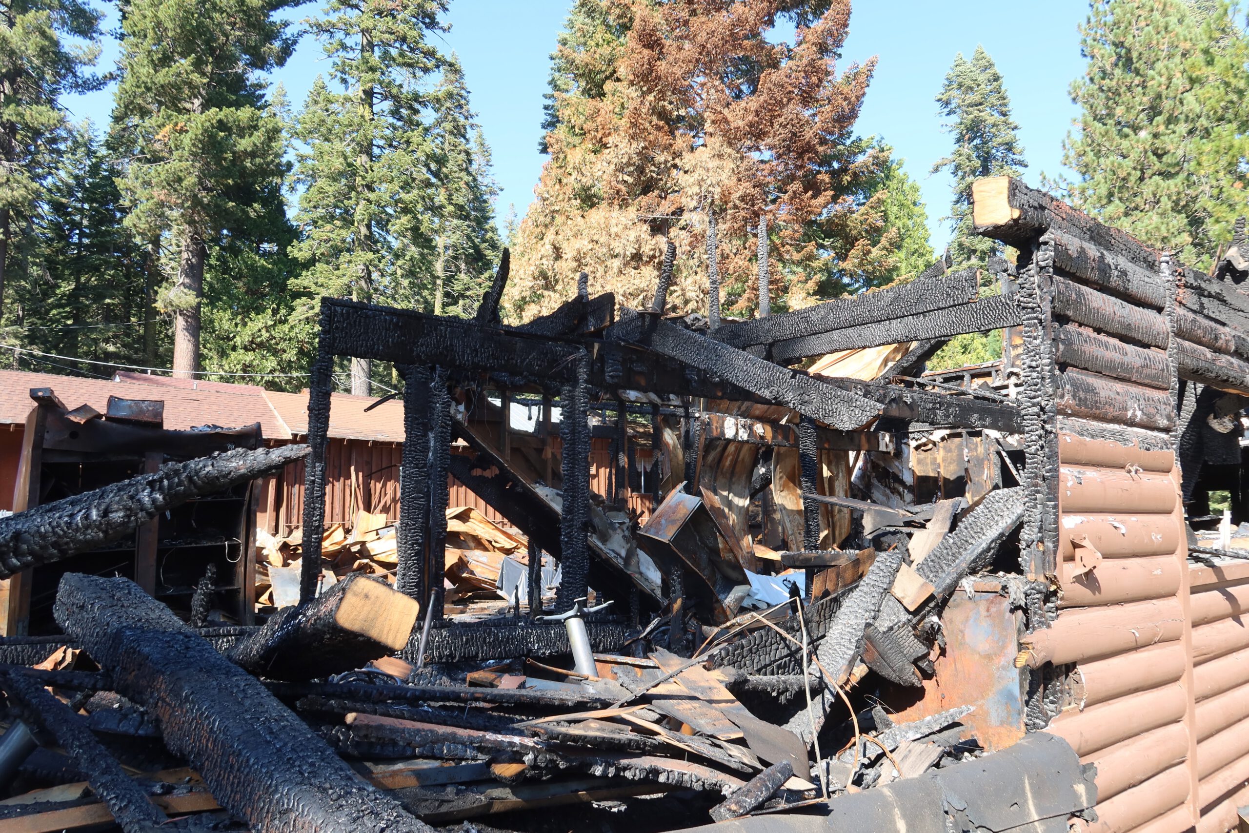 Burned main lodge at Bear River Lake Resort after the 2023 fire in Amador County, California, showing charred beams and fire damage