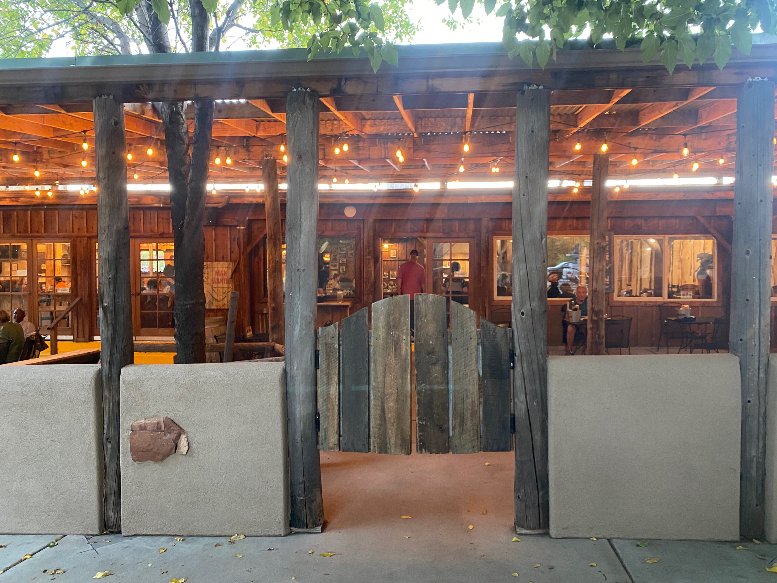 Outdoor seating at Iron Horse Kanab Utah with wooden western style patio, warm string lights, rustic fence entrance and cozy evening atmosphere in downtown Kanab