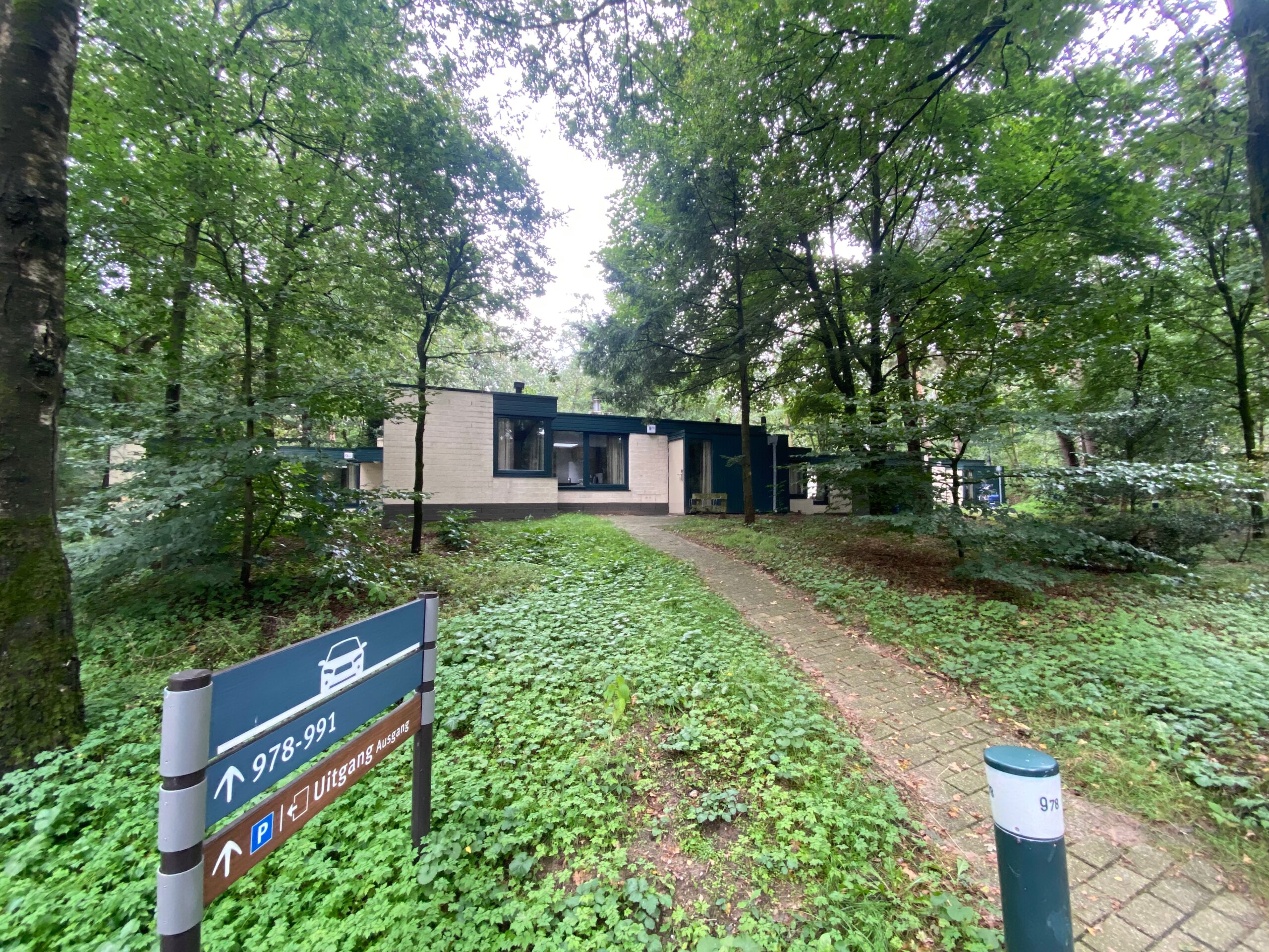 Exterior view of Center Parcs Het Heijderbos VIP cottage 978 in the forest of Heijen, showing private path entrance and cottage number signage