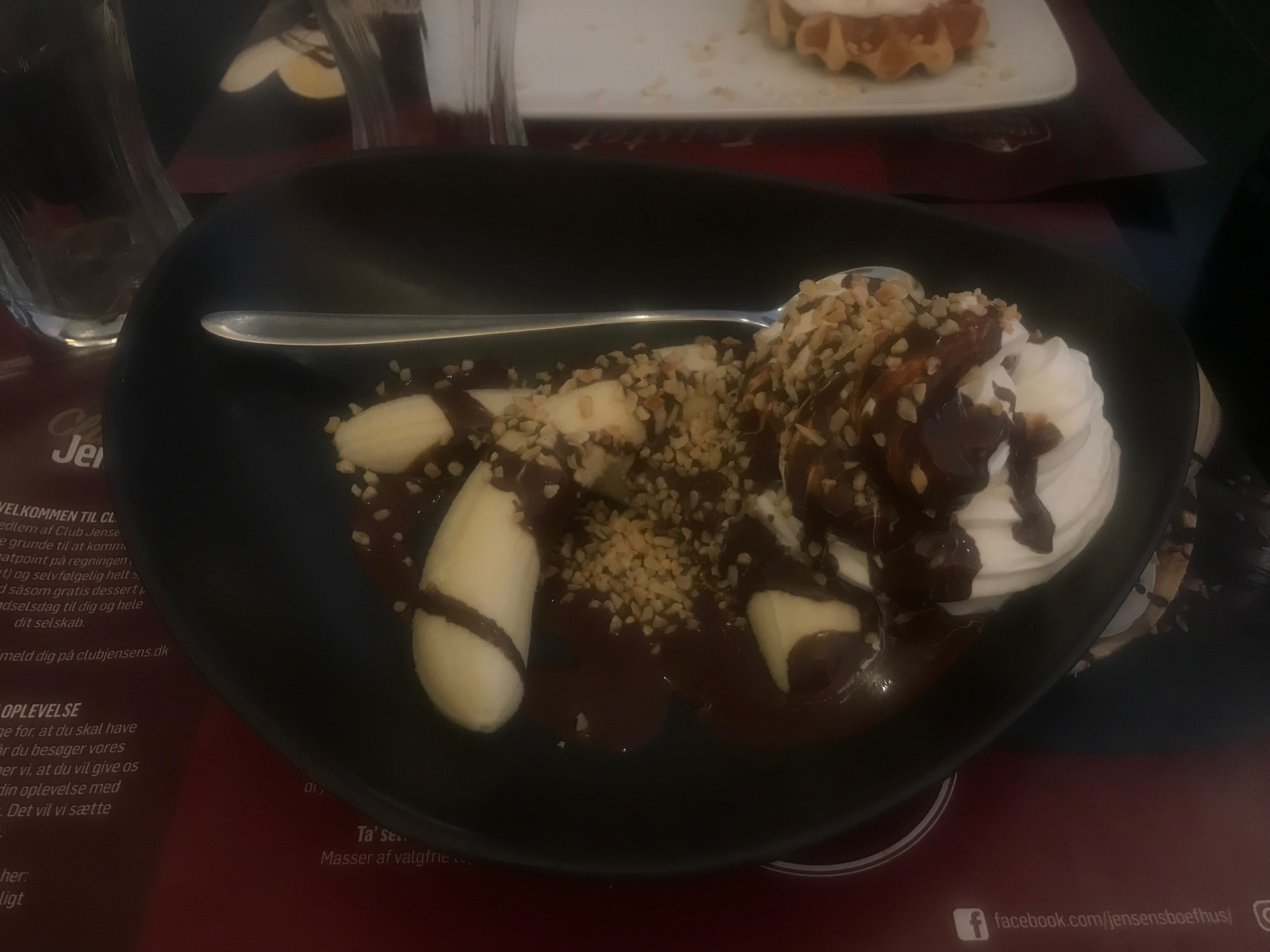 Jensens Bofhus Sonderborg review showing a banana split dessert with chocolate sauce whipped cream and chopped nuts after our meal in Sønderborg Denmark