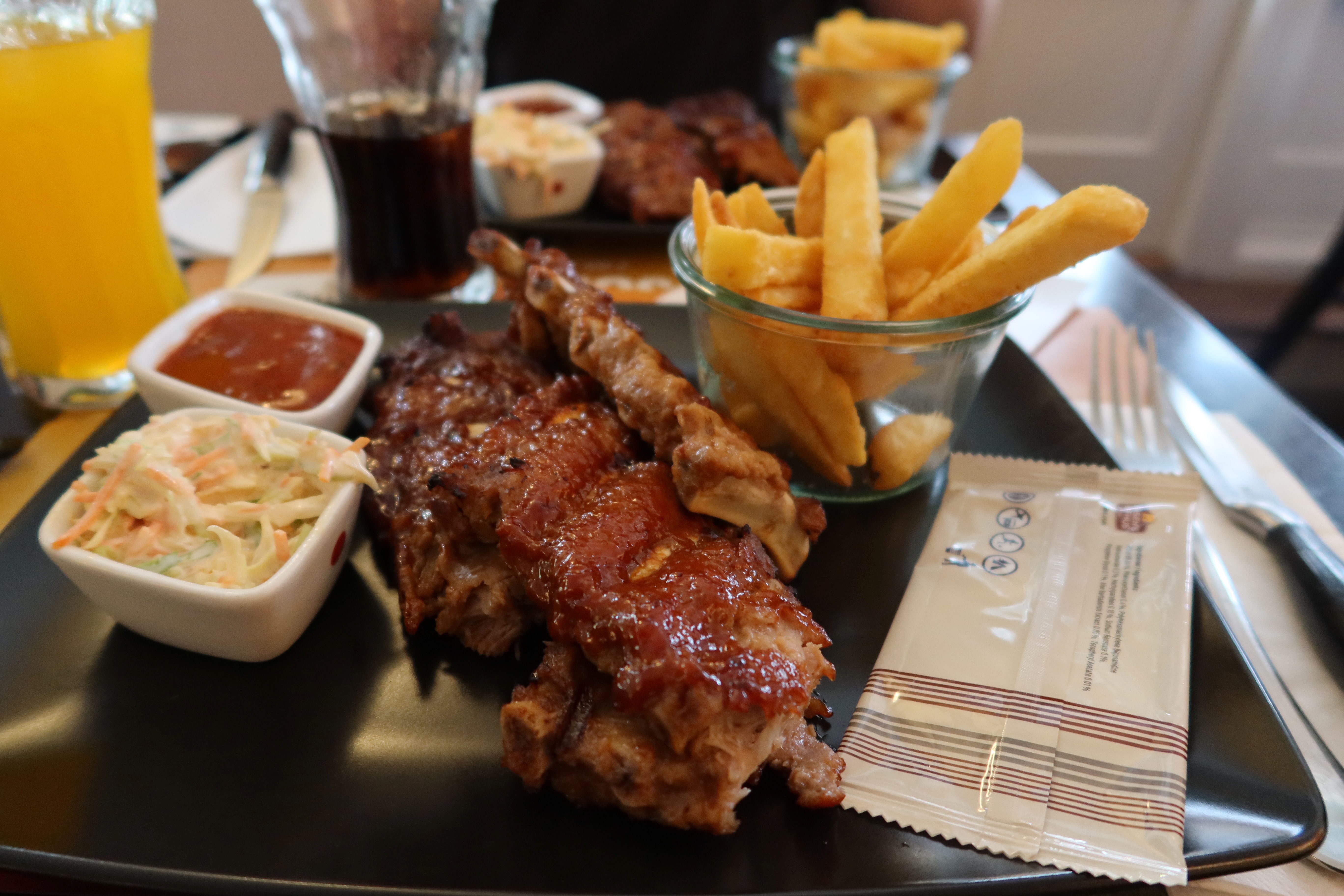 Jensens Bofhus Sonderborg review showing barbecue ribs thick fries coleslaw sauce and large soft drinks during our meal in Sønderborg Denmark