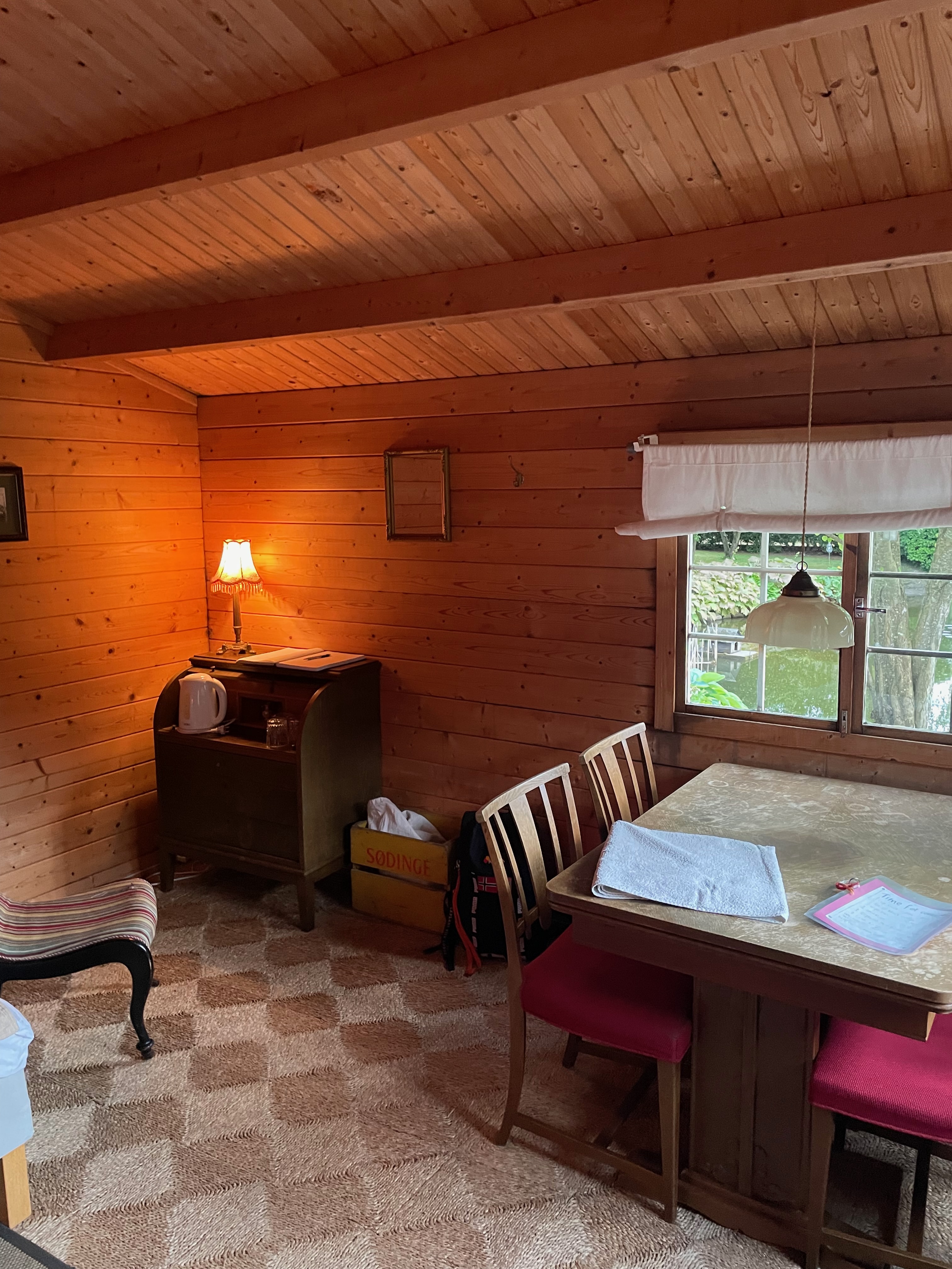 Annekset pa Langholm review showing the cozy wooden Airbnb hut interior with dining table chairs window kettle warm lamp and rustic wood walls in Ringe Denmark