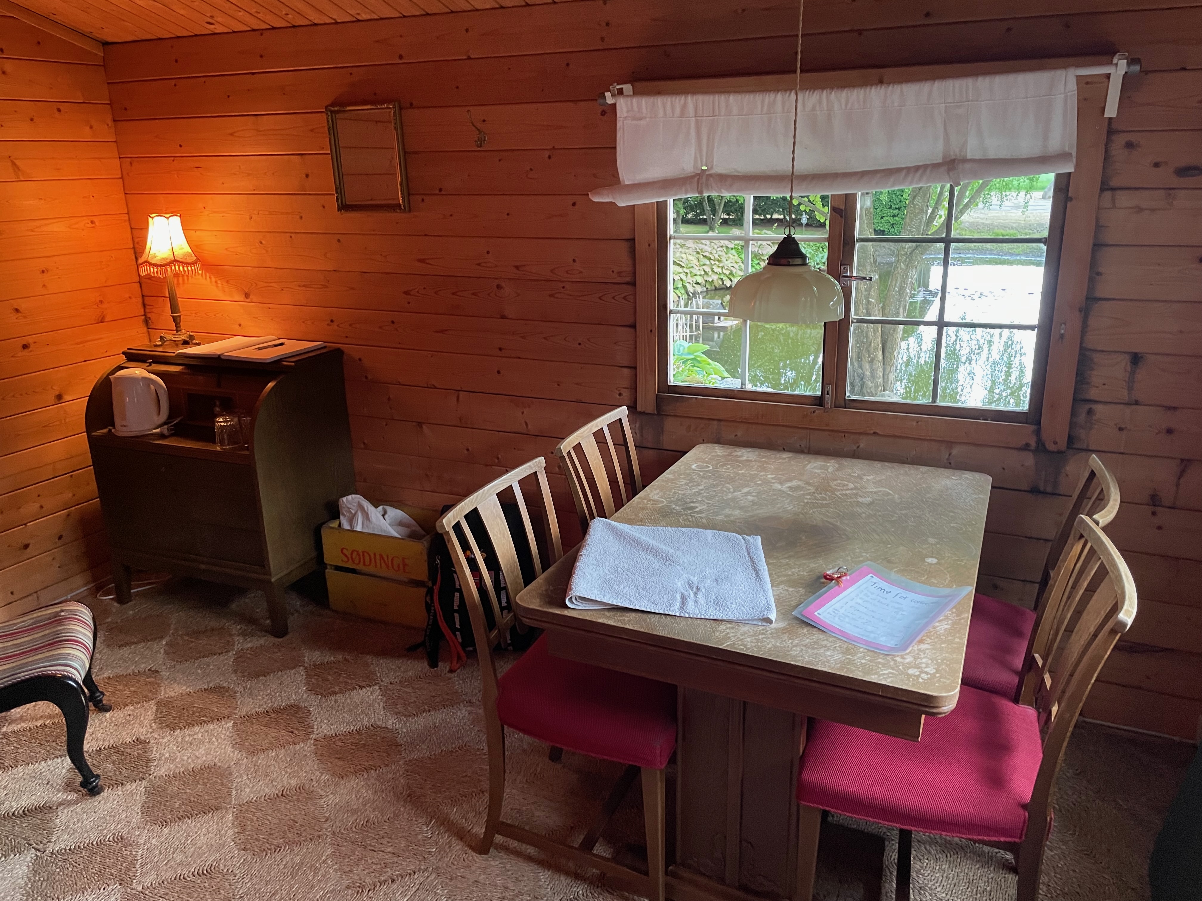 Annekset pa Langholm review showing the wooden Airbnb hut interior with dining table chairs window view kettle towel warm lamp and rustic wood walls in Ringe Denmark