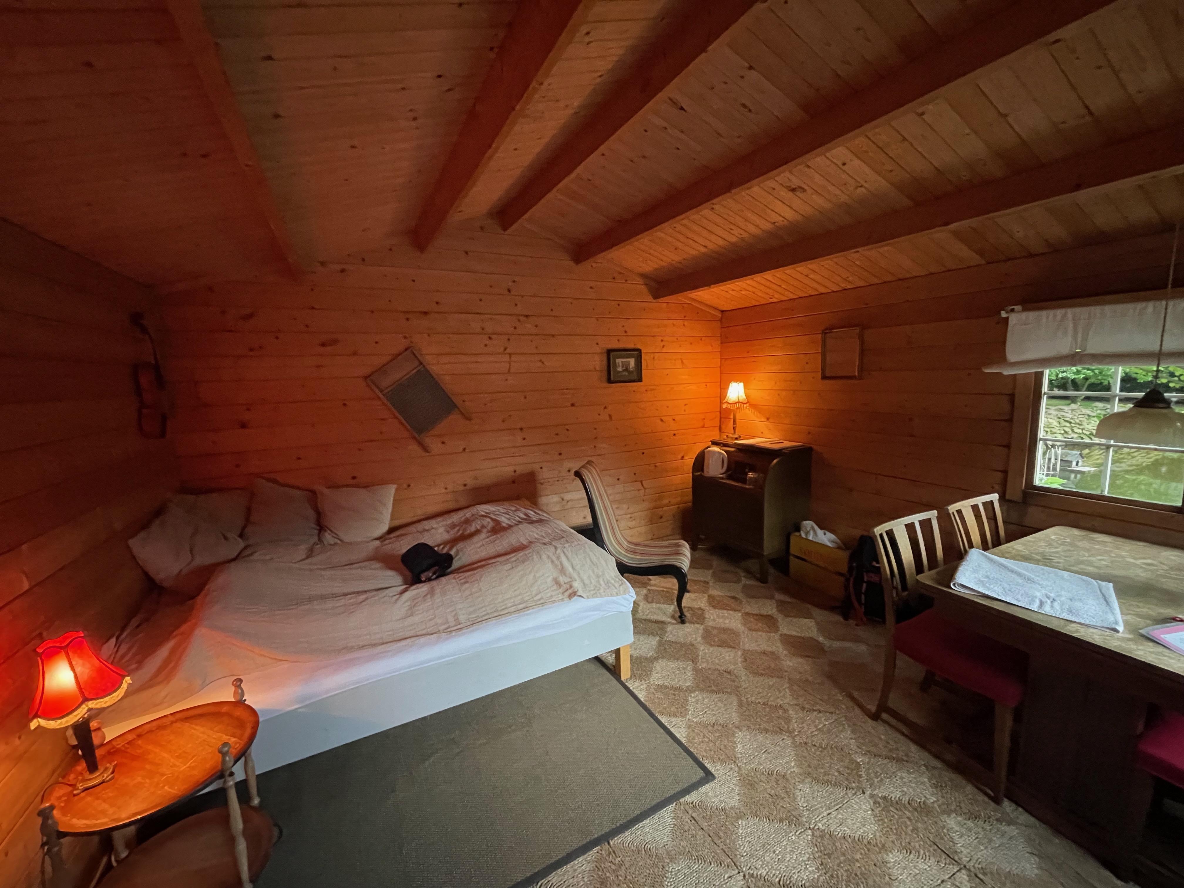 Annekset pa Langholm review showing the cozy wooden Airbnb hut interior with bed dining table chairs warm lamps rustic wood walls and window view in Ringe Denmark