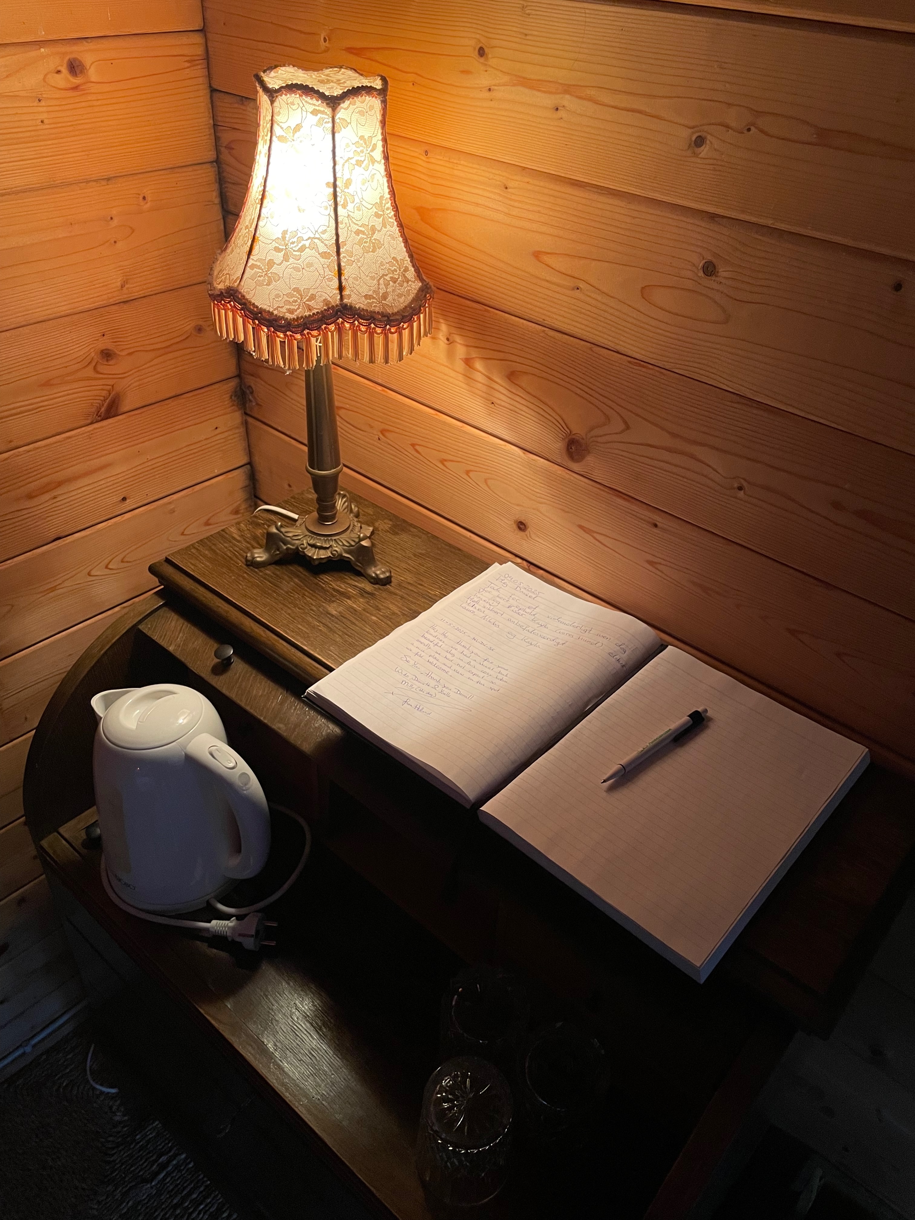 Annekset pa Langholm review showing a warm wooden hut corner with vintage lamp guestbook pen kettle glasses and rustic wood walls in Ringe Denmark