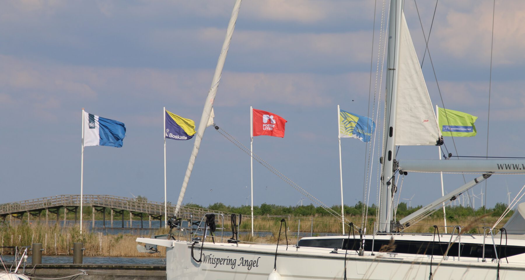 Marker Wadden island visit with a sailboat in the harbor and visible flags from Boskalis, Postcode Loterij, Natuurmonumenten and Marker Wadden