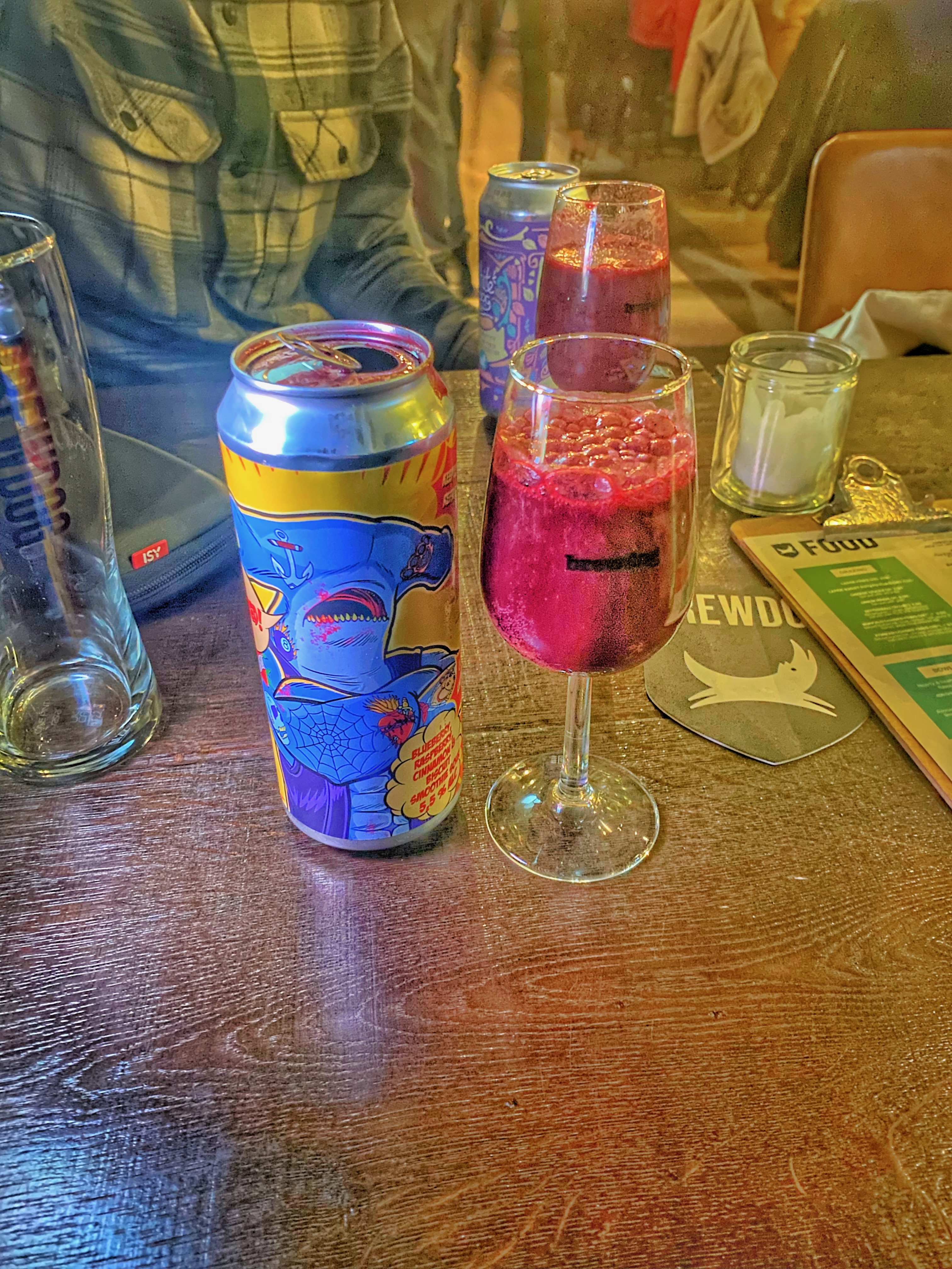BrewDog Outpost Rotterdam Review with colorful craft beer cans pink beer in BrewDog glasses wooden table BrewDog coaster and warm bar atmosphere