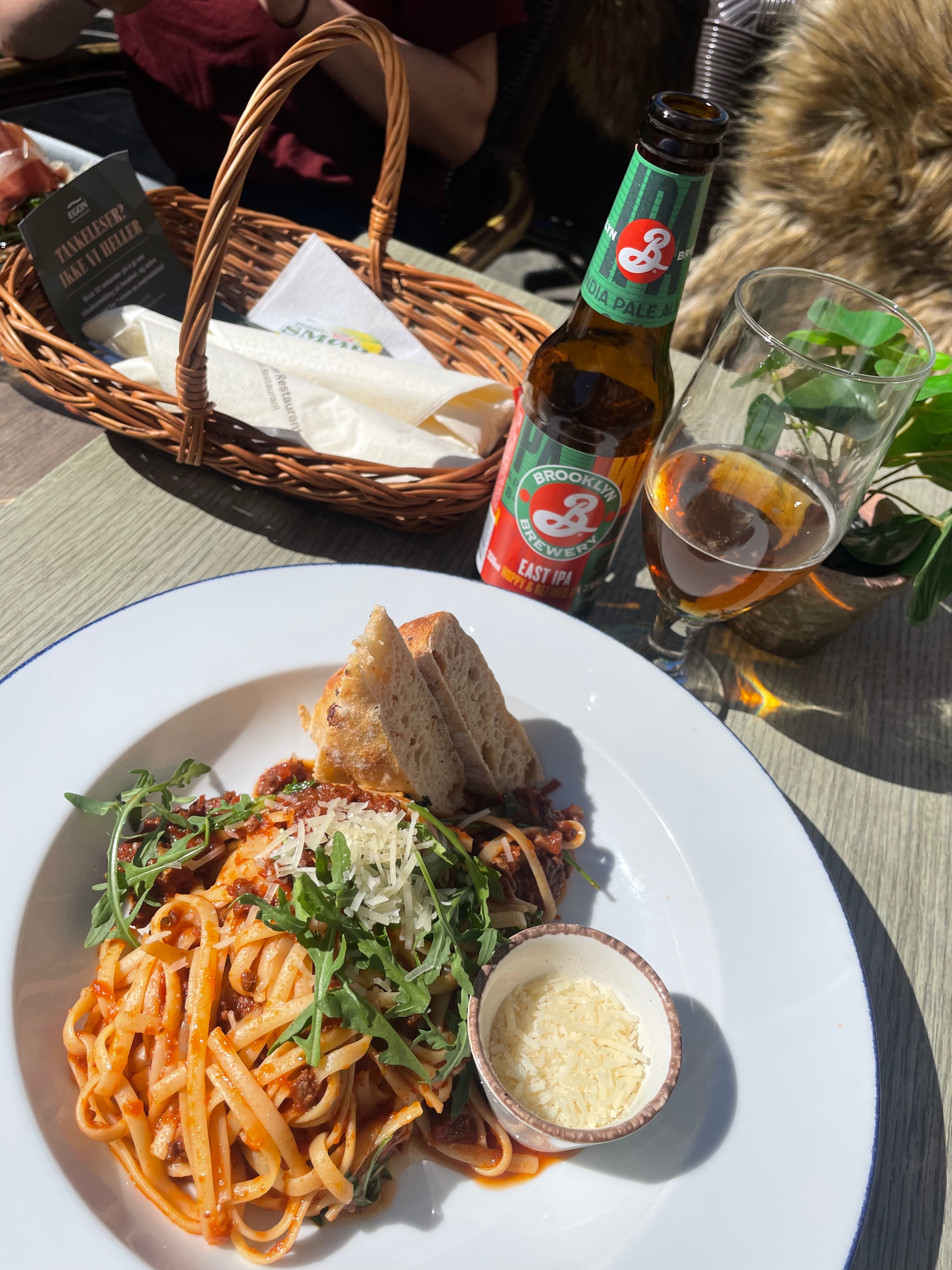 Pasta Bolognese with bread, parmesan, arugula, and Brooklyn Brewery East IPA on the sunny terrace at Egon Karl Johan in Oslo.