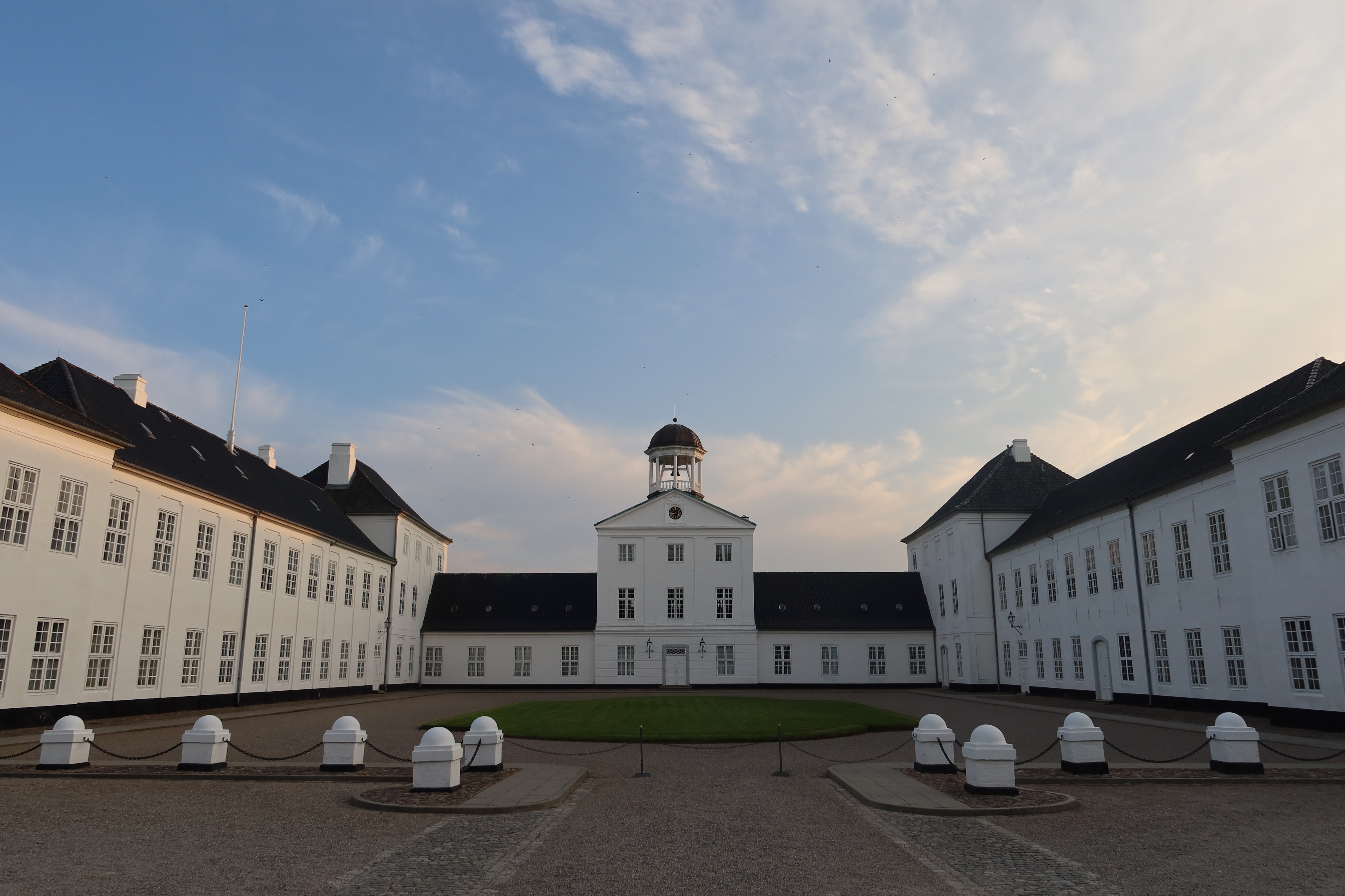 Gråsten Slot main courtyard with the white royal palace wings, central tower, and evening sky in Southern Denmark.