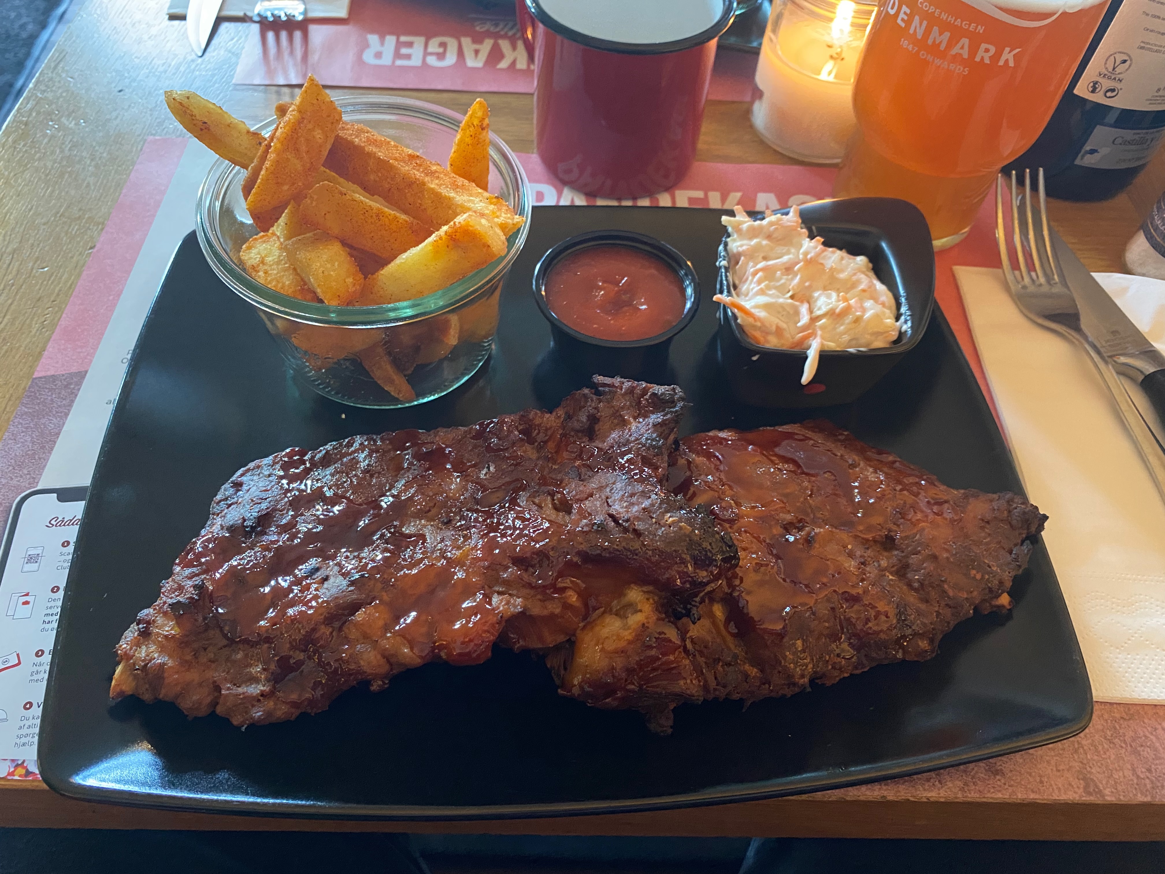 Jensens Bofhus Silkeborg review showing a plate of glazed spare ribs seasoned fries sauce coleslaw and a cold Carlsberg beer inside the former restaurant in Silkeborg Denmark