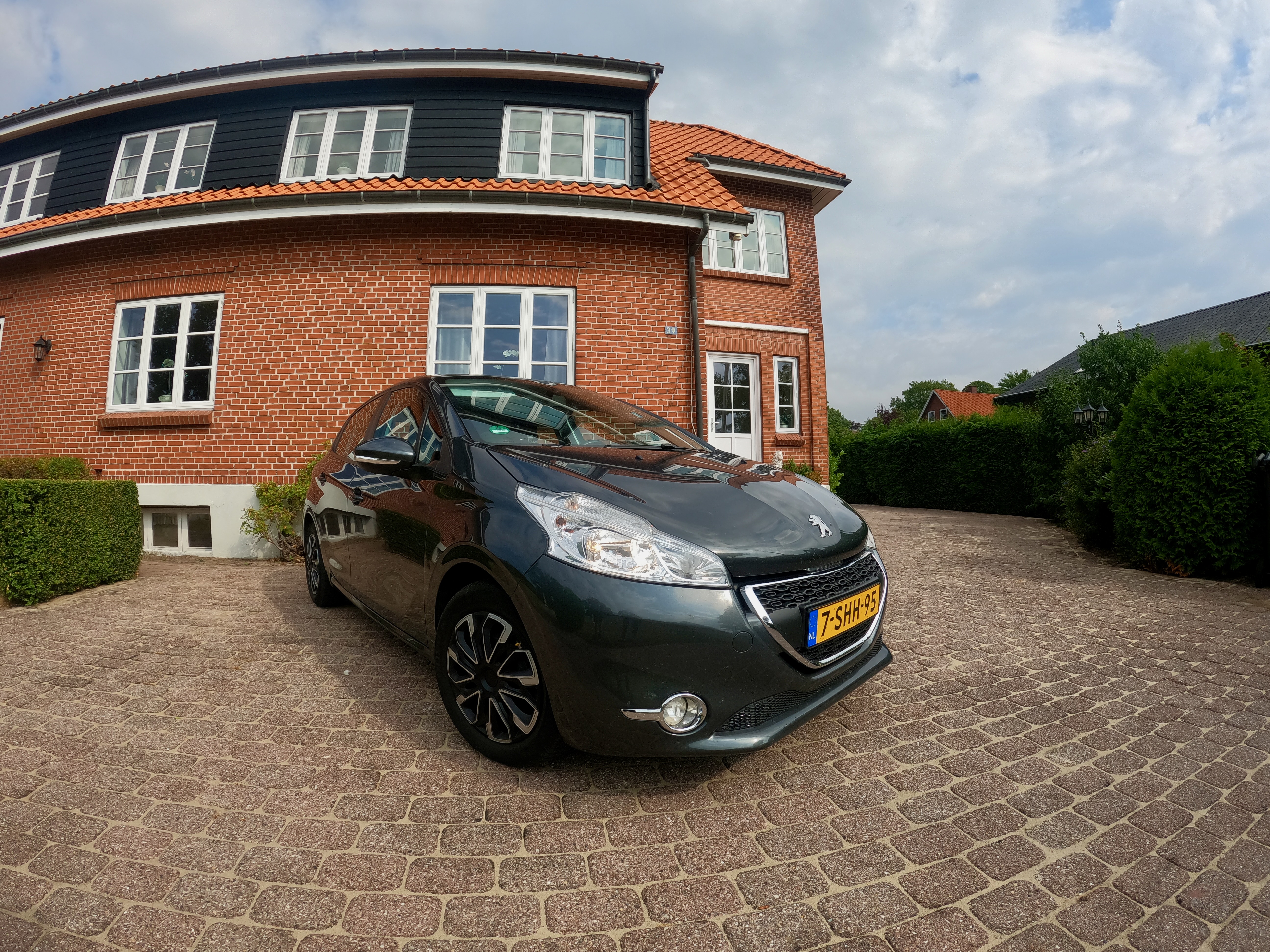Kollund Rooms Review photo showing a Peugeot 208 parked on the driveway in front of the red brick guesthouse in Kollund Østerskov, Denmark.