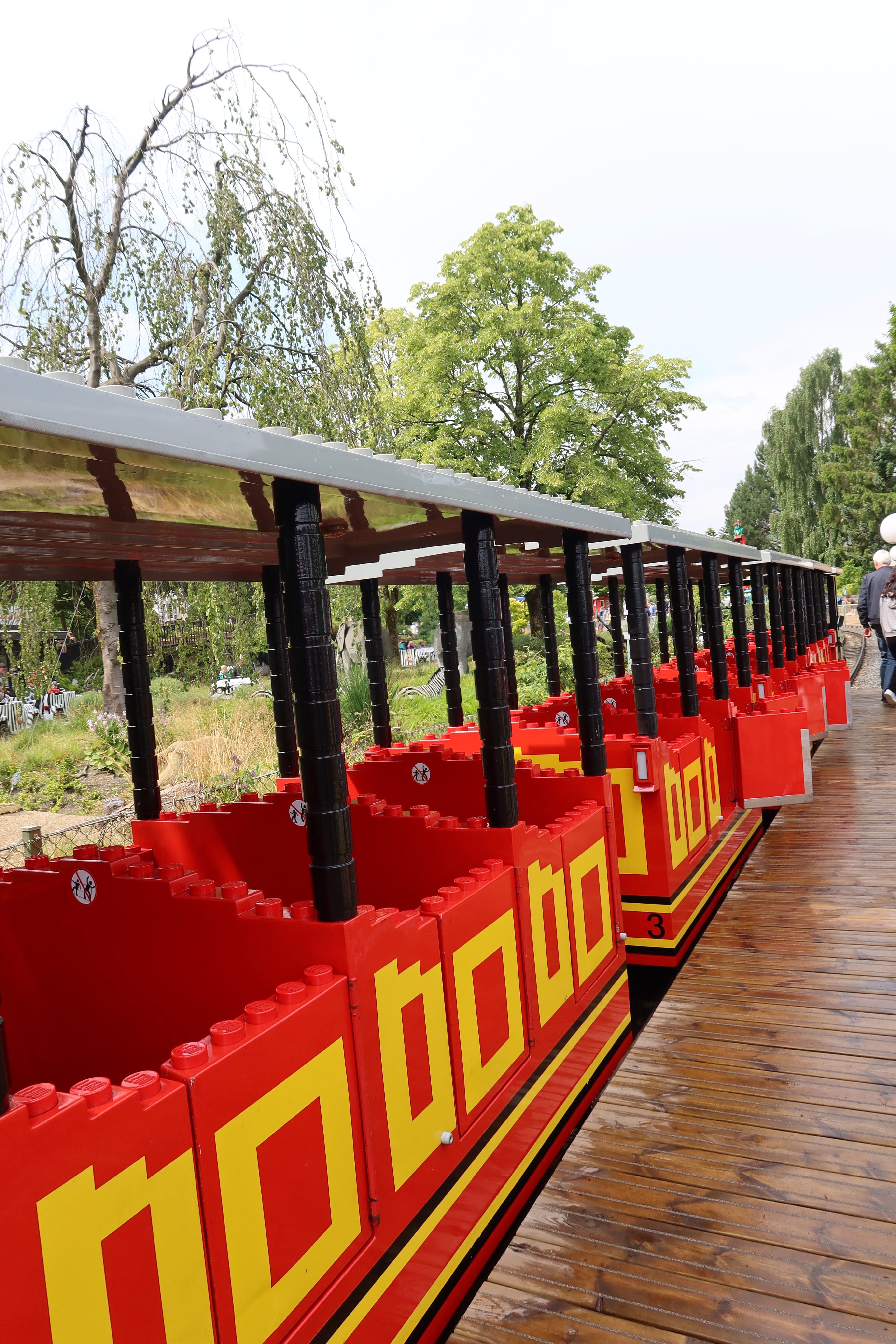 LEGOLAND Billund review IMG 2810 showing the red LEGO styled LEGOLAND train waiting at the station with trees and park scenery in Billund Denmark