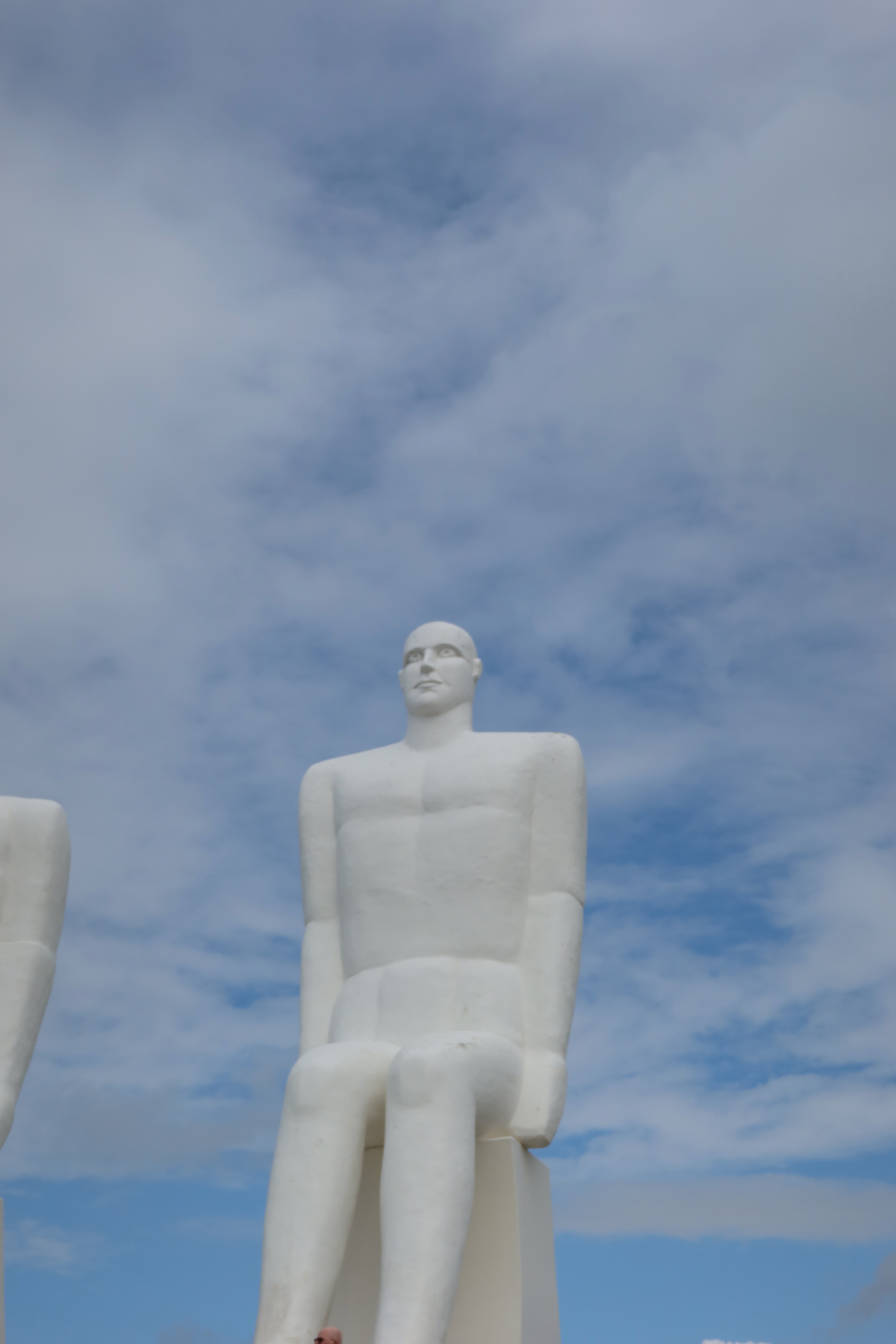 Mennesket ved Havet in Esbjerg Denmark with a close view of one giant white statue under a cloudy blue sky