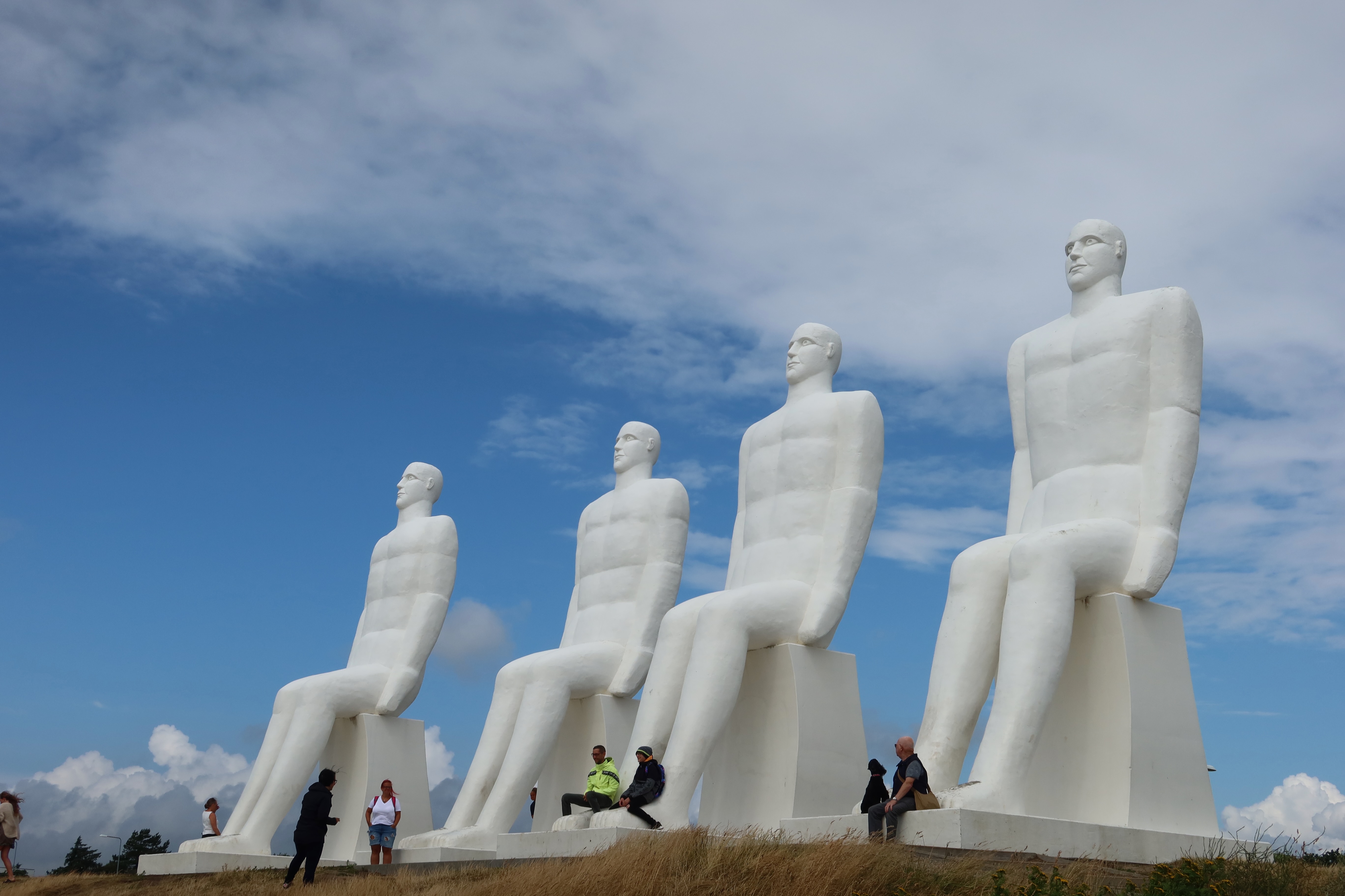 Mennesket ved Havet in Esbjerg Denmark with visitors standing beneath the four giant white coastal statues