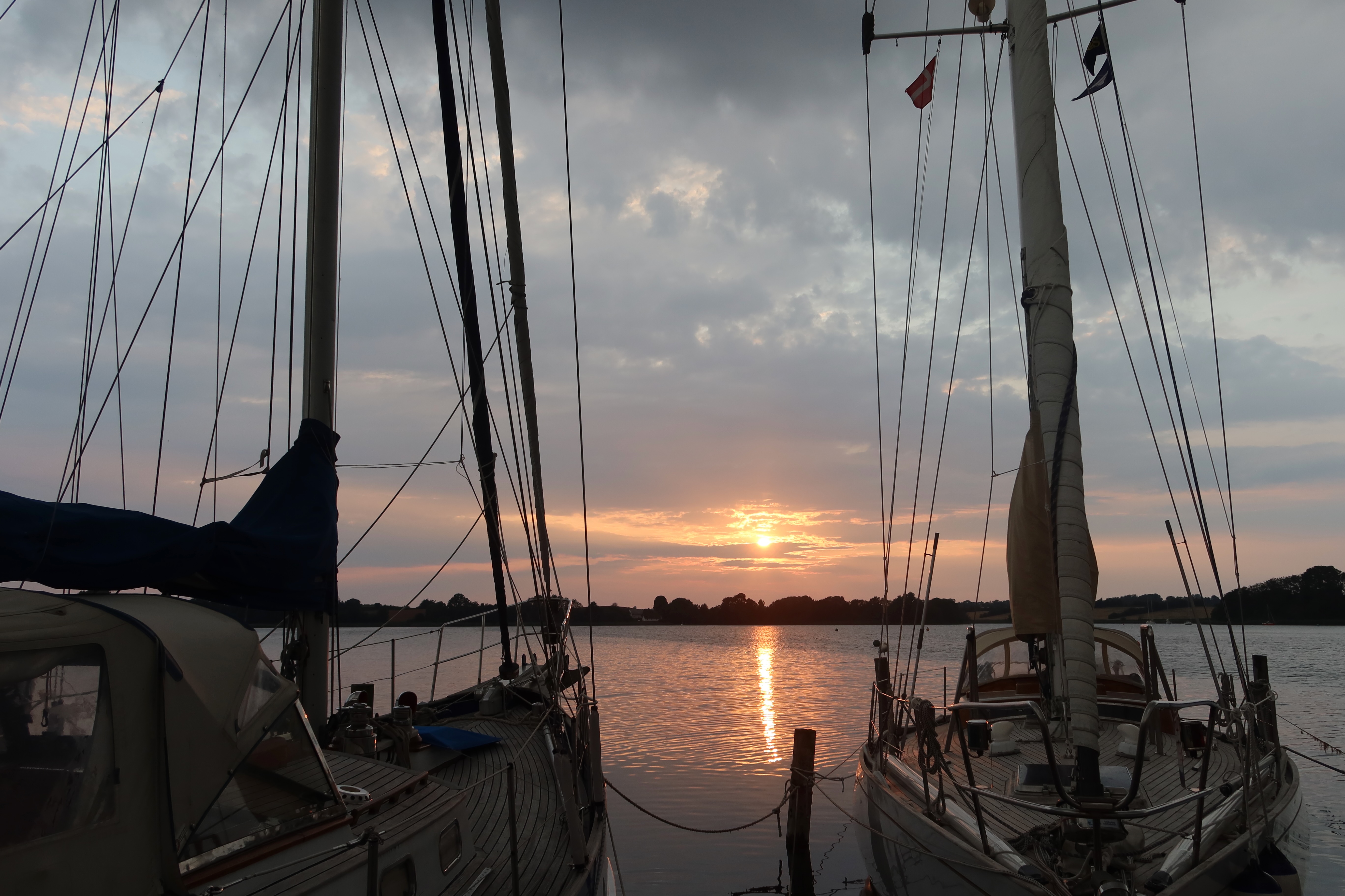 Mjelsgaard 1 Airbnb Review showing a peaceful sunset at Mjelsvig Marina in Denmark with sailboats, calm water, and a warm evening sky near the Airbnb