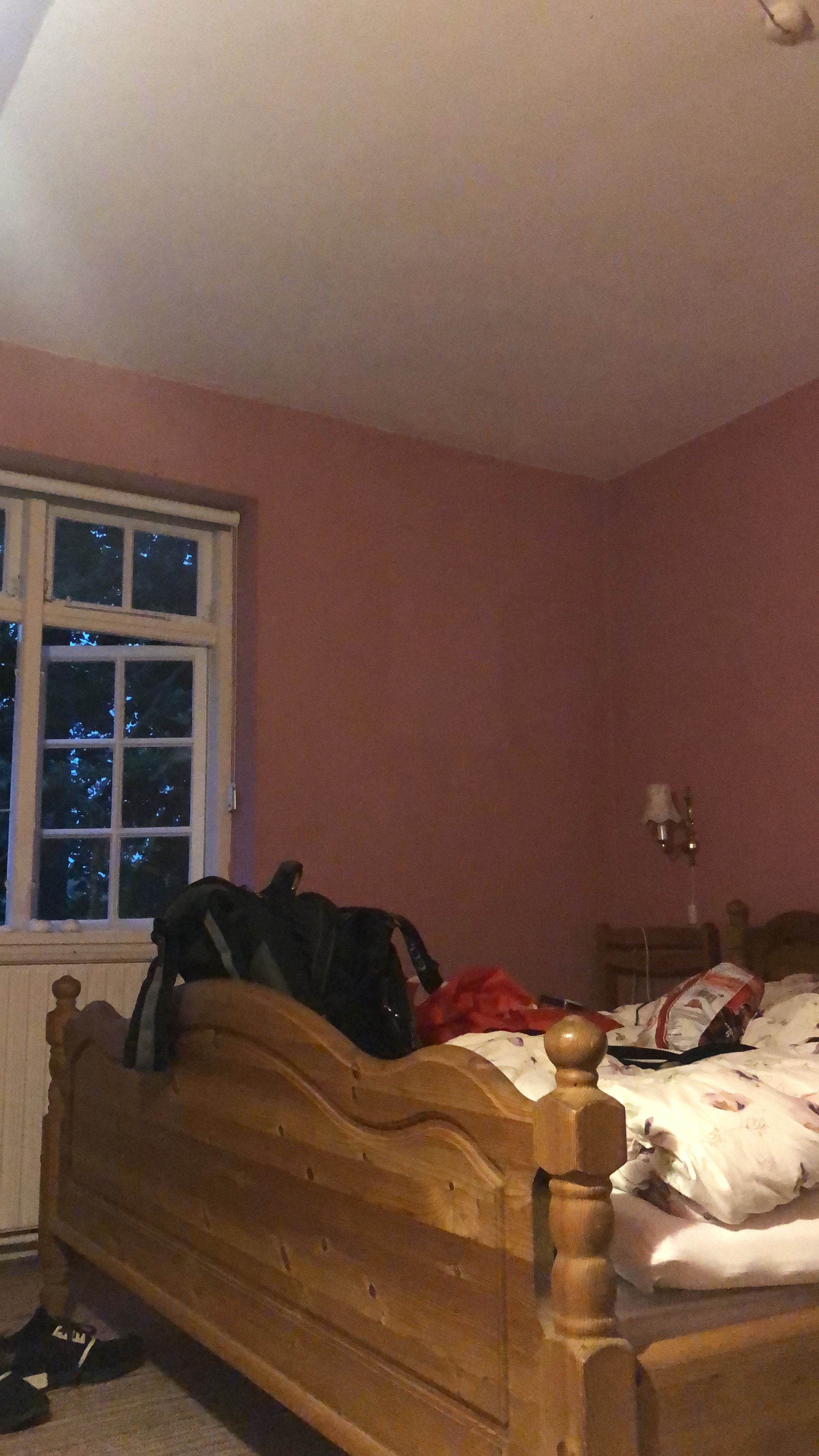 Mjelsgaard 1 Airbnb Review showing the pink bedroom with a wooden bed, travel bags, soft evening light, and a simple countryside Airbnb atmosphere in Denmark