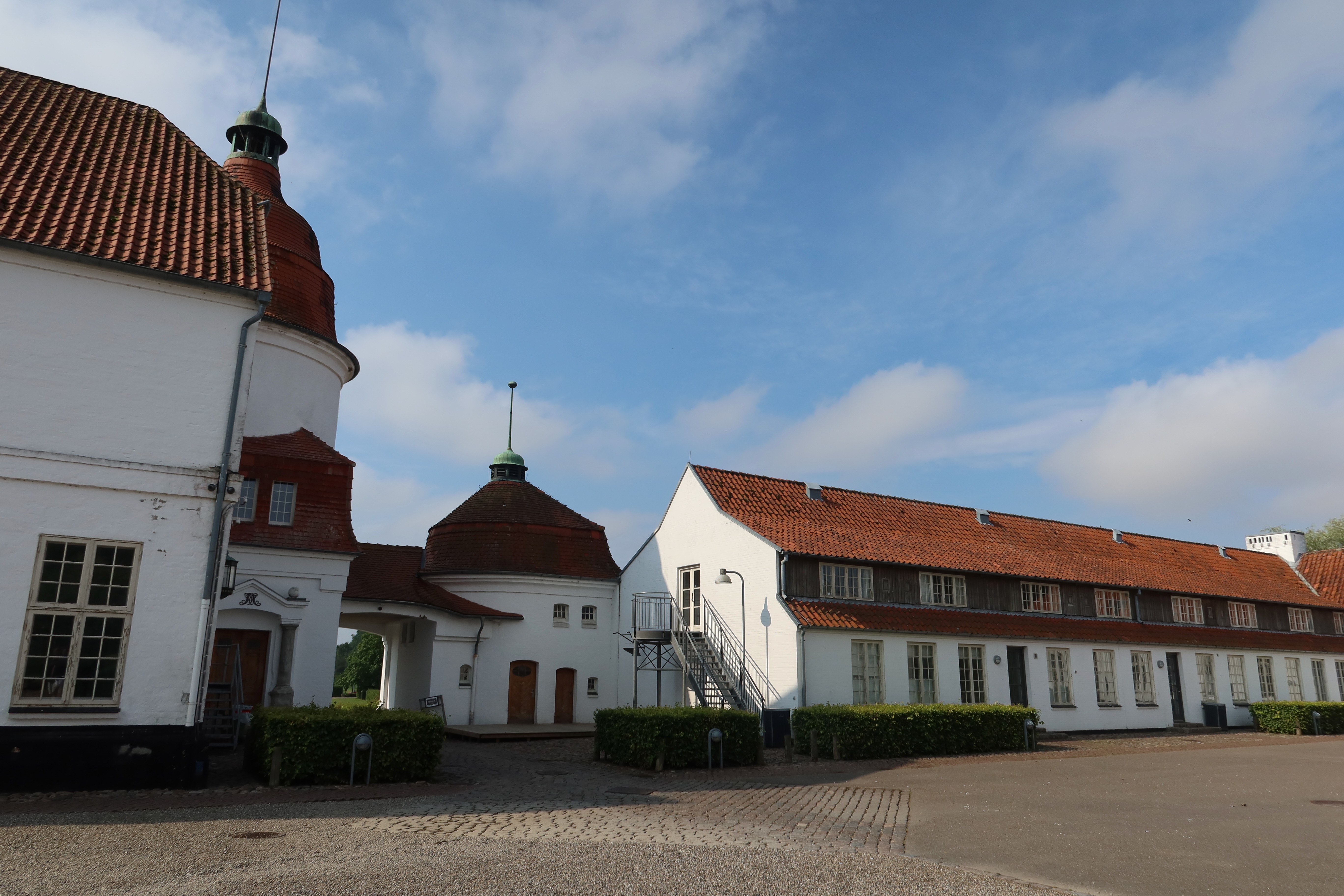 Nordborg Slot courtyard with white castle buildings red tiled roofs round tower and blue sky in Nordborg Denmark