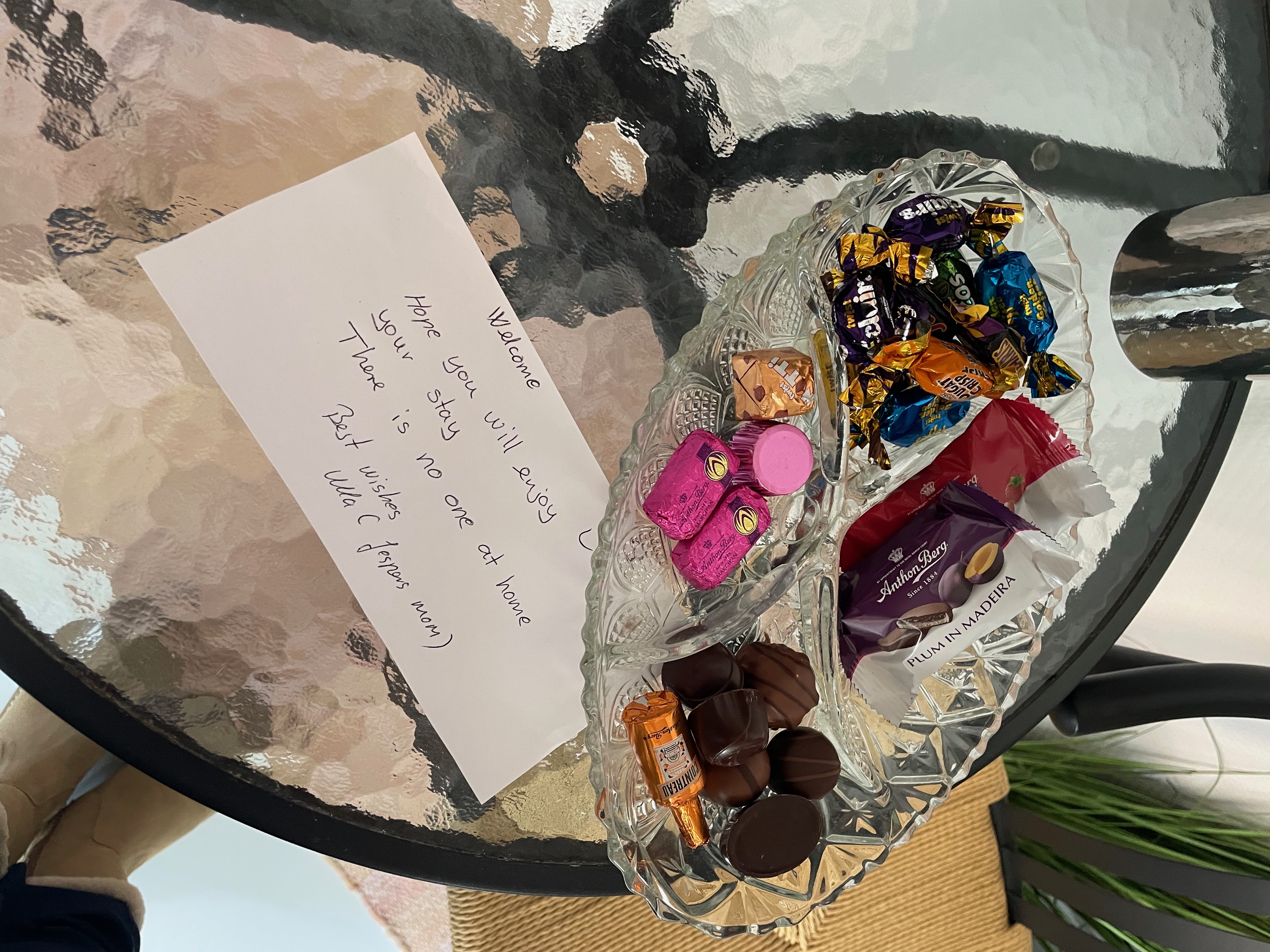Private Annex Haderslev Review showing a handwritten welcome note and candy tray inside the Airbnb annex in Haderslev, with chocolates, snacks and a glass table.