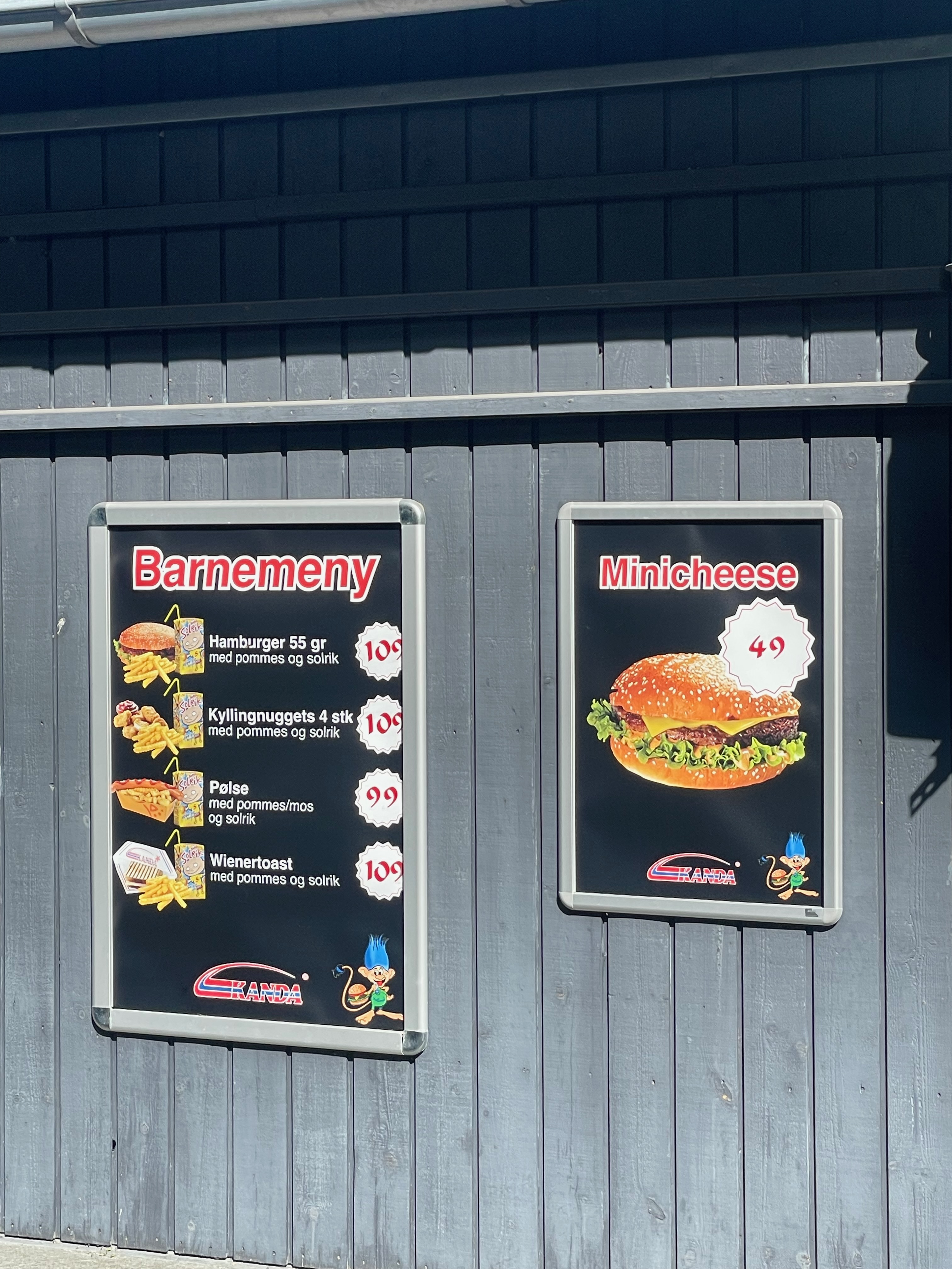 Tollerud rasteplass syd kids menu and Minicheese signs on the dark wooden wall, showing burger, fries, chicken nuggets, hot dog, wiener toast and small cheeseburger options at the roadside restaurant in Norway