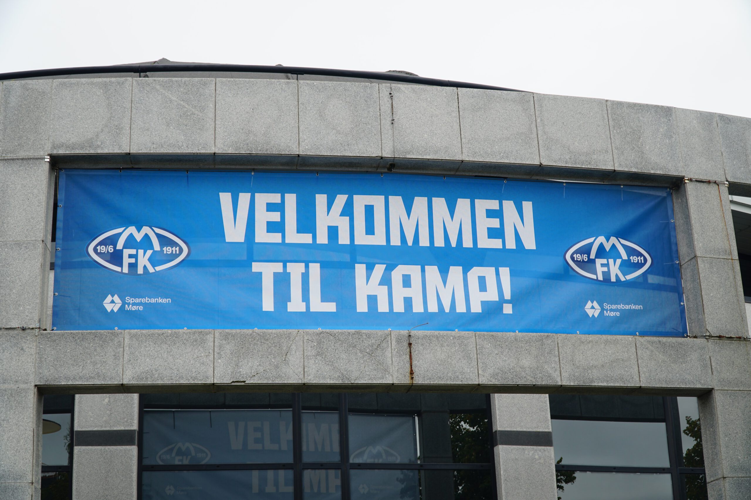 Aker Stadion Molde main entrance banner reading “Velkommen til kamp” with Molde FK logos and sponsor Sparebanken Møre displayed above the stadium entrance.