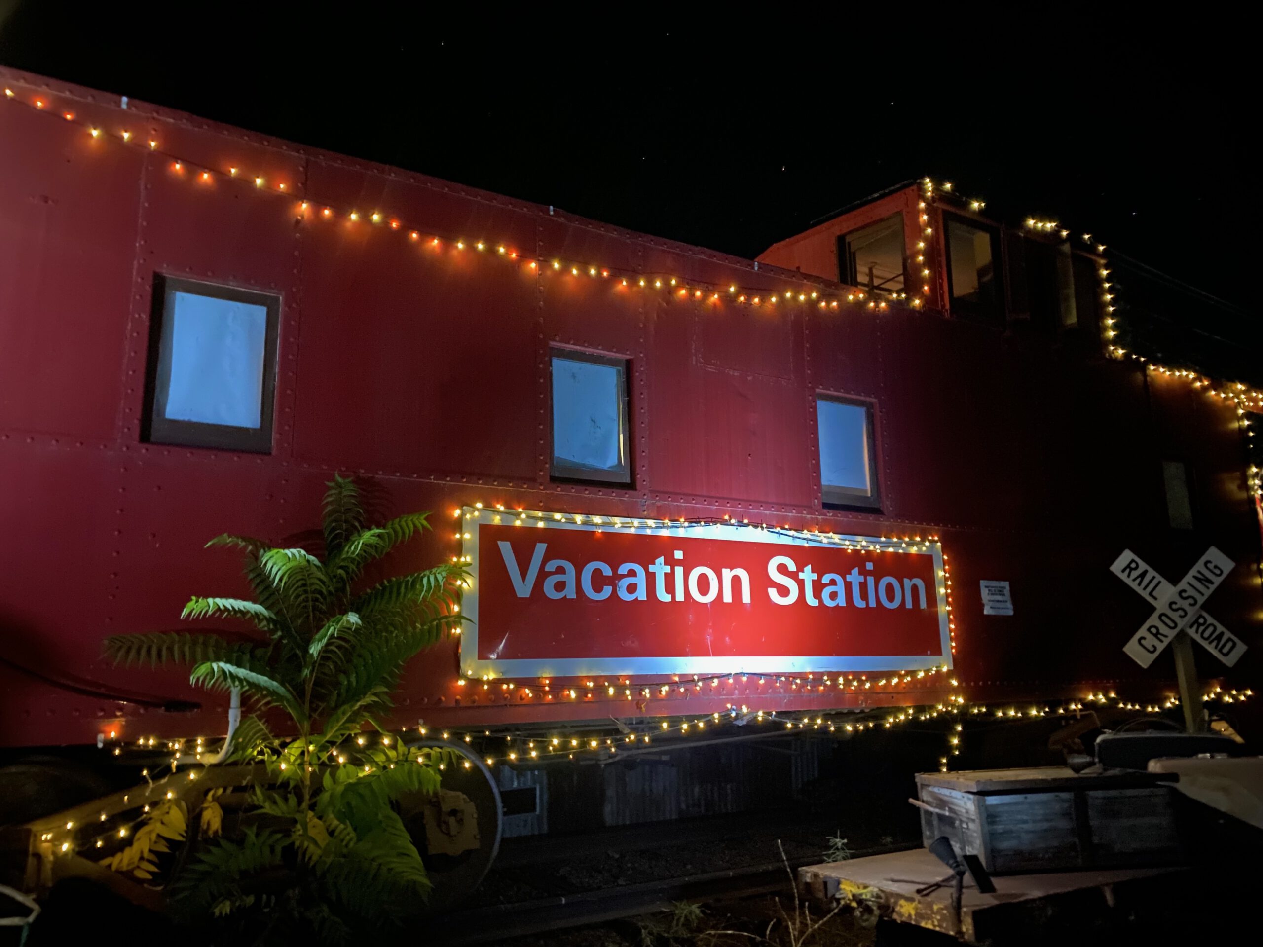 Vacation Station Coulterville caboose at night, red train car illuminated with string lights, cozy Airbnb stay in rural California near Yosemite National Park