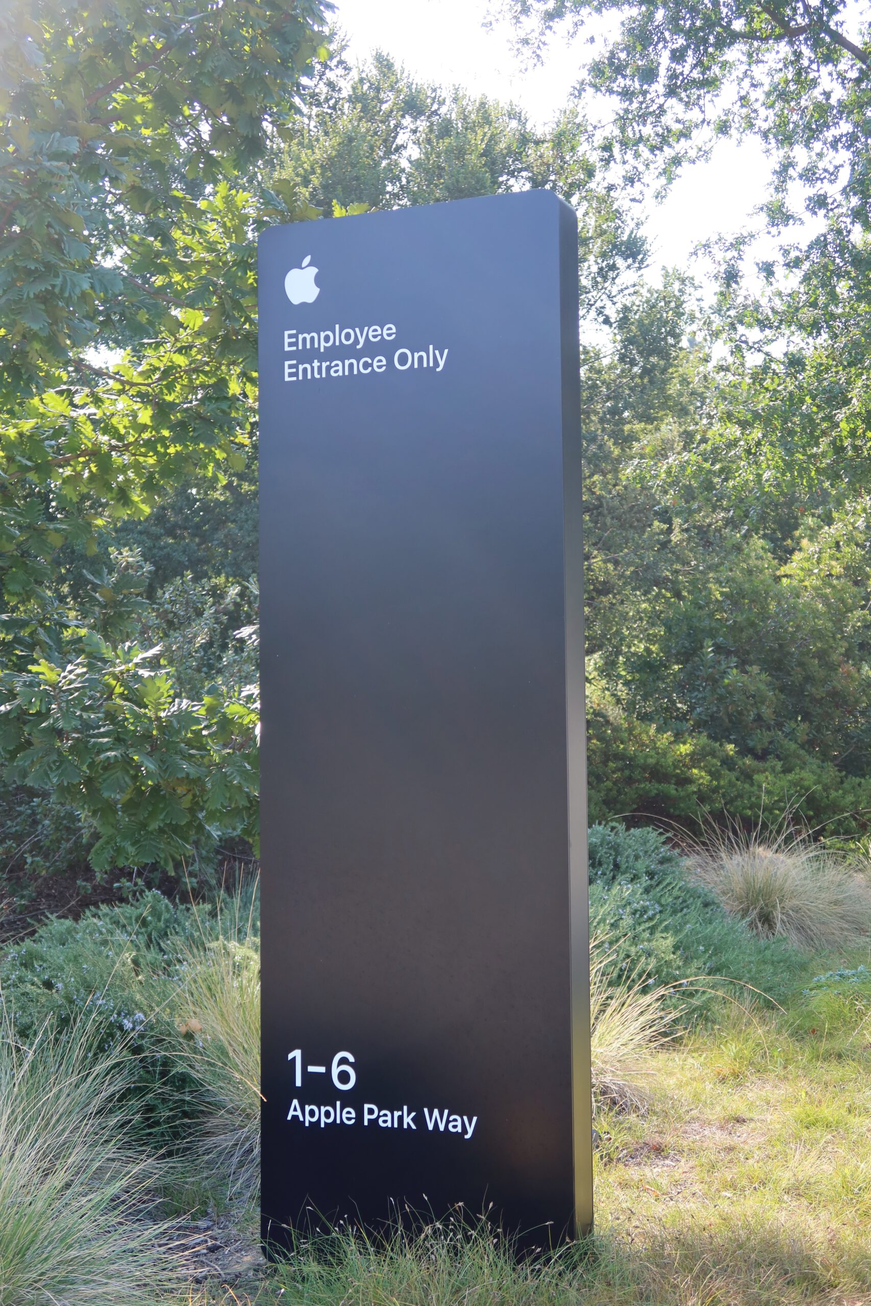 Apple Park employee-only entrance sign at 1-6 Apple Park Way in Cupertino, surrounded by greenery and trees outside Apple’s headquarters.