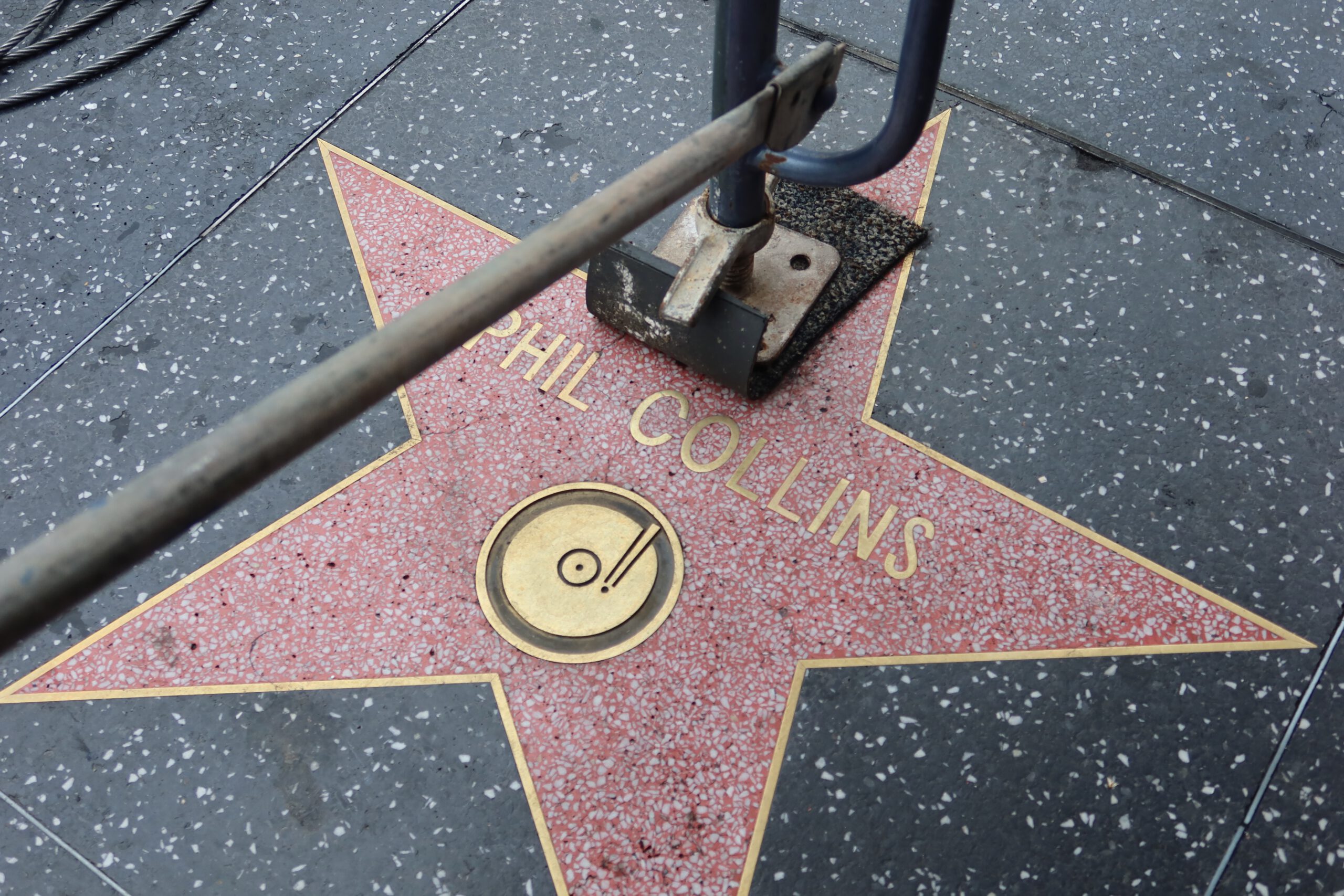 Phil Collins’ star on the Hollywood Walk of Fame in Los Angeles, partially framed by a street barrier on Hollywood Boulevard.