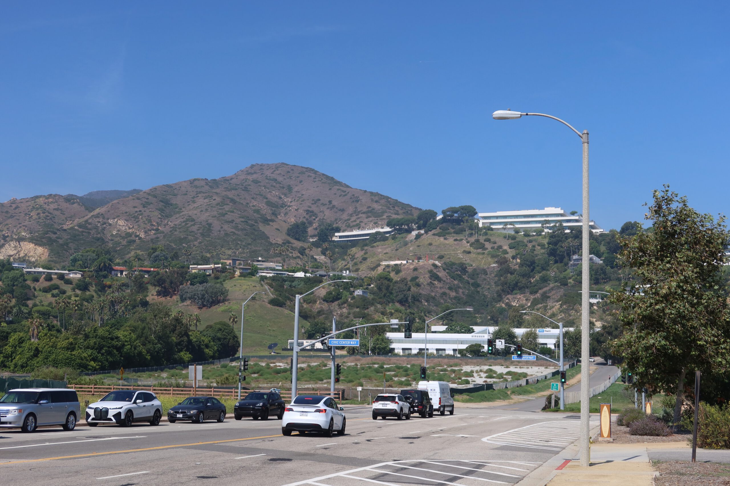 Street view along Civic Center Way in Malibu, California with hills, modern buildings, and clear blue sky