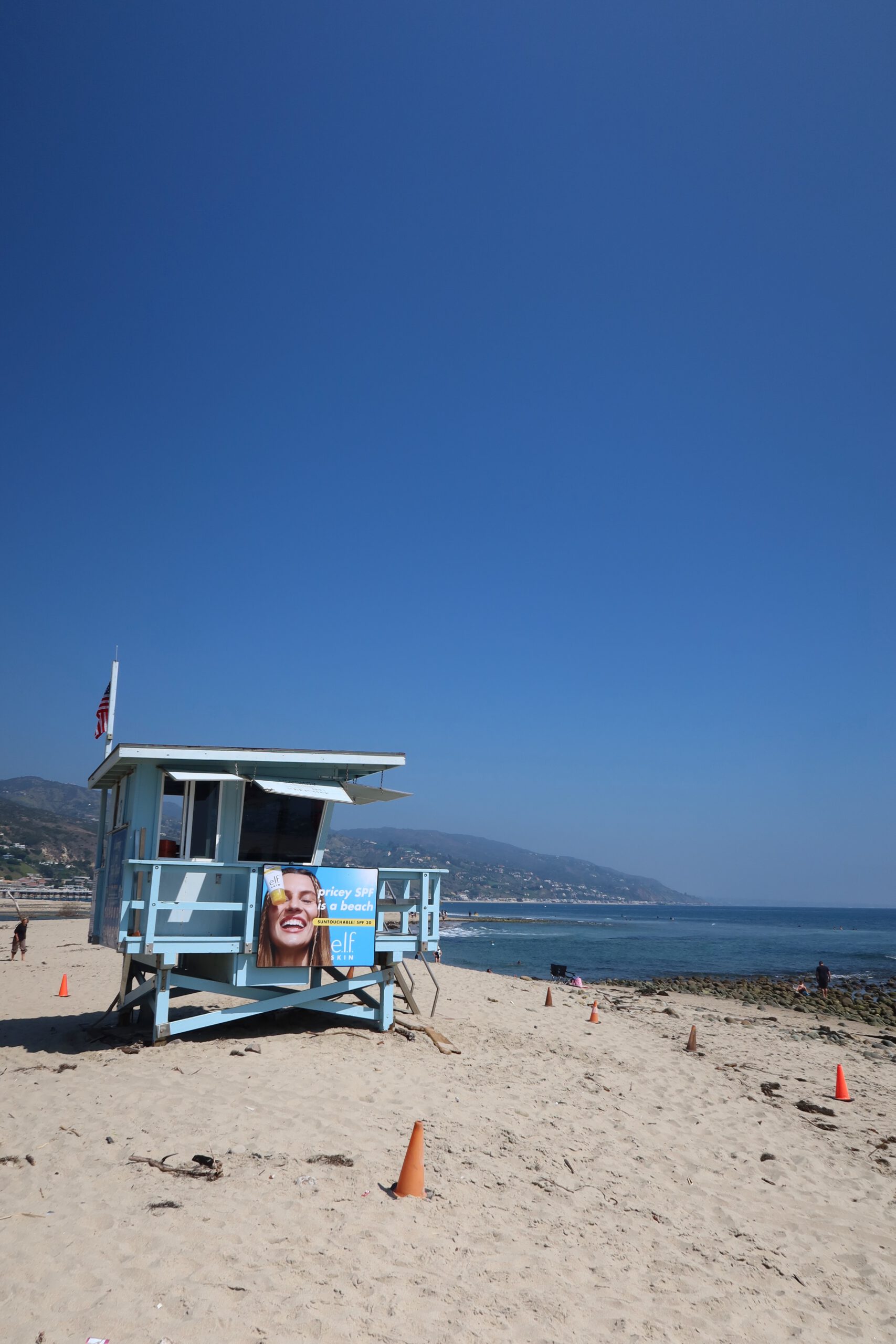 Light blue lifeguard tower on Malibu Lagoon State Beach with Pacific Ocean, sandy beach, and clear blue sky