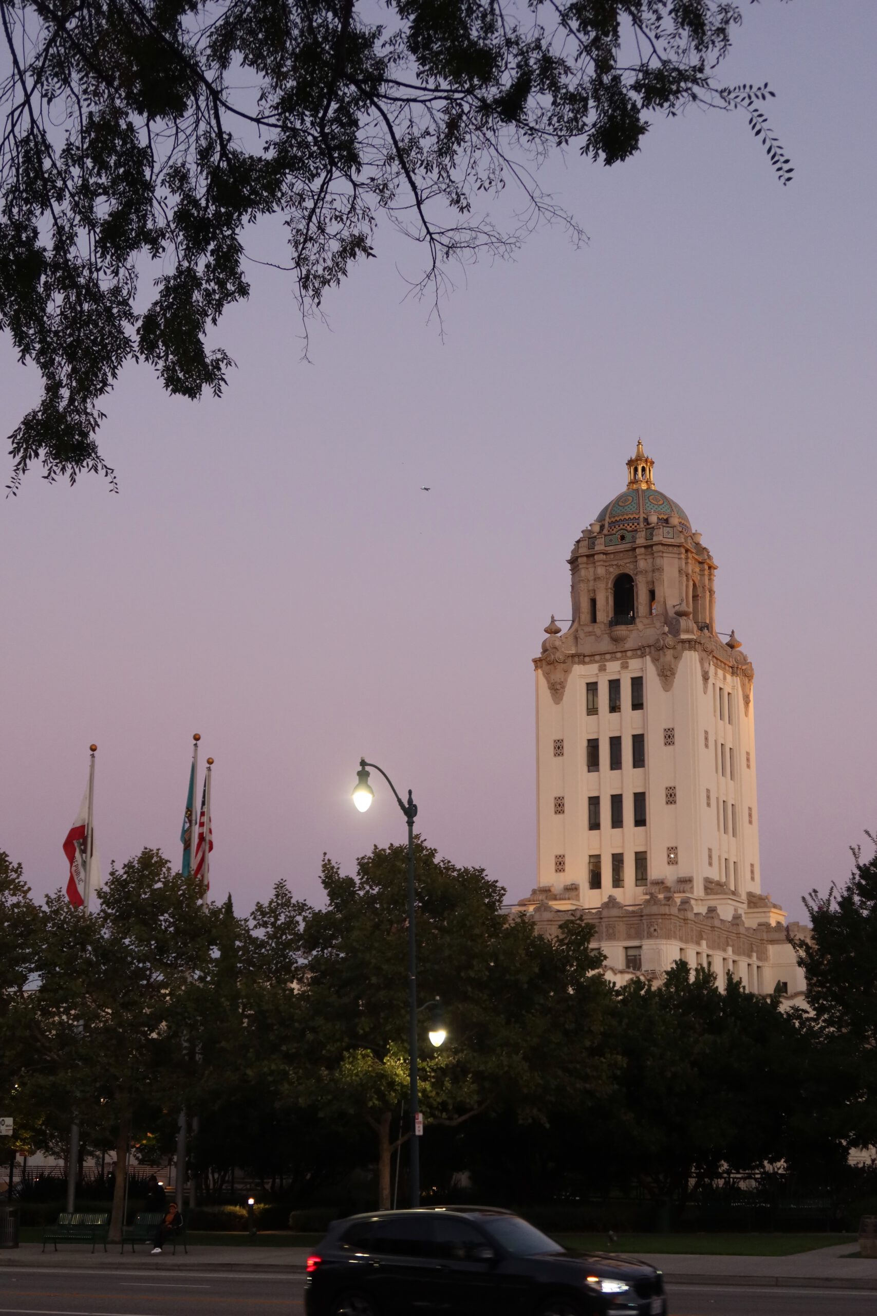 Beverly Hills City Hall tower at dusk with California and US flags and streetlights
