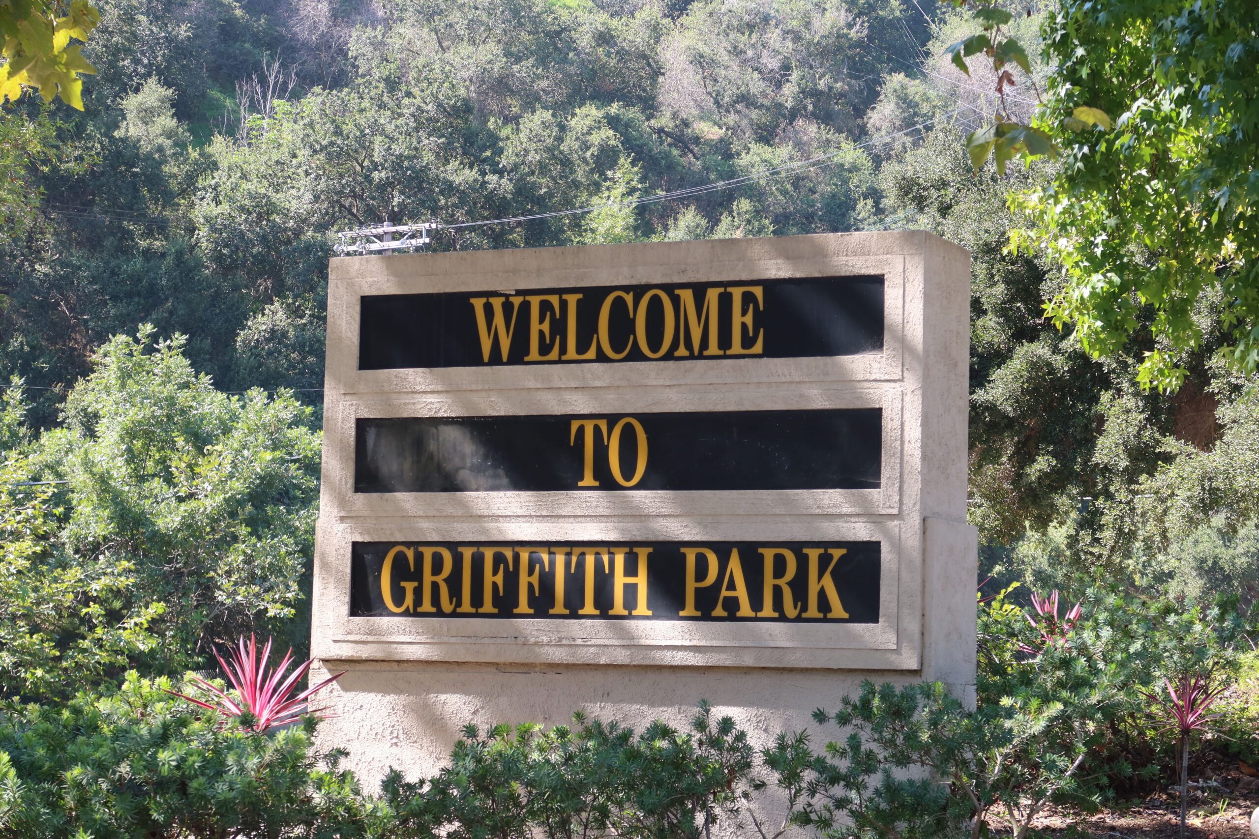 Stone welcome sign reading “Welcome to Griffith Park,” surrounded by greenery and trees at the entrance of Griffith Park in Los Angeles.