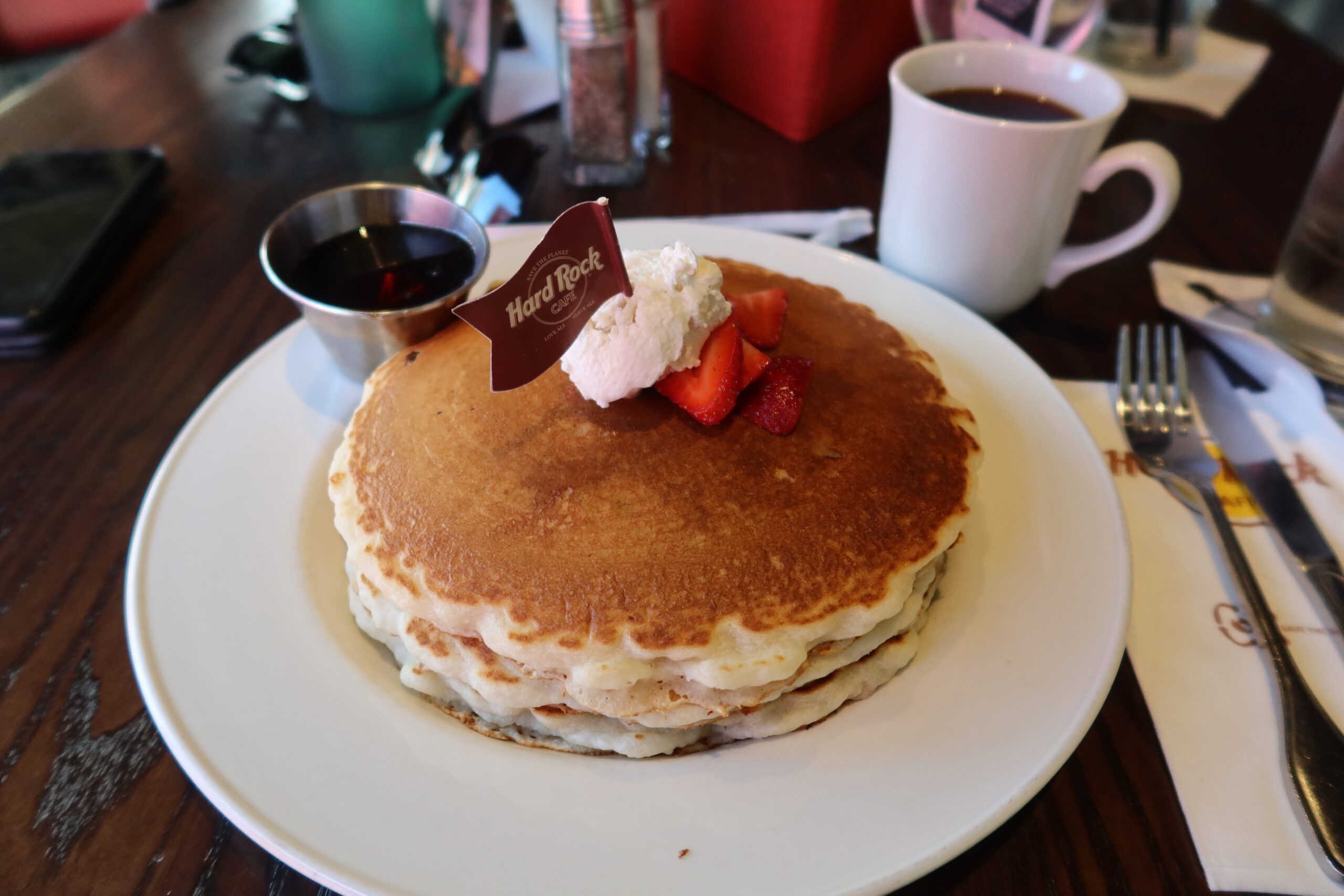 Stack of fluffy American pancakes with whipped cream, fresh strawberries, and maple syrup at Hard Rock Cafe Las Vegas Strip.