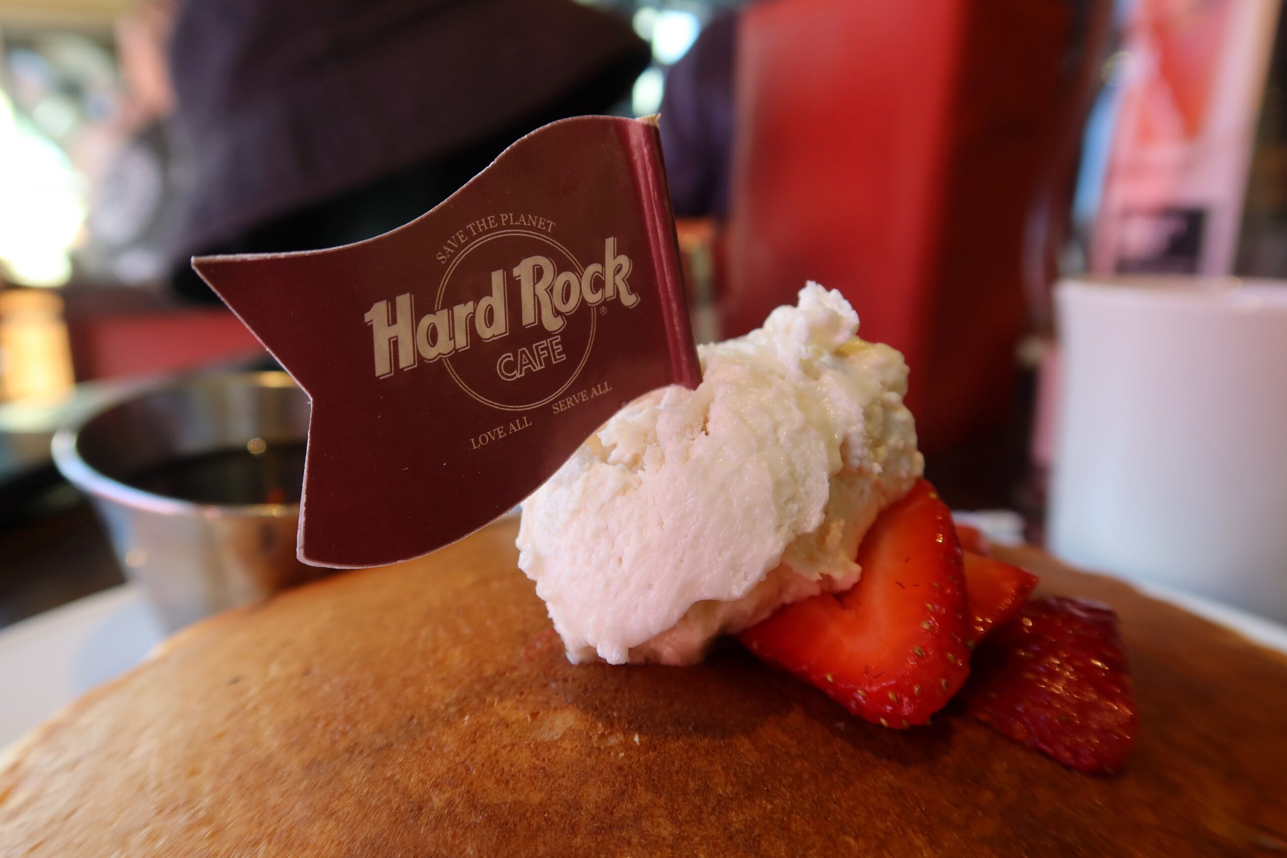 Close-up of American pancakes topped with whipped cream and strawberries, featuring a Hard Rock Cafe flag at the Las Vegas Strip location.