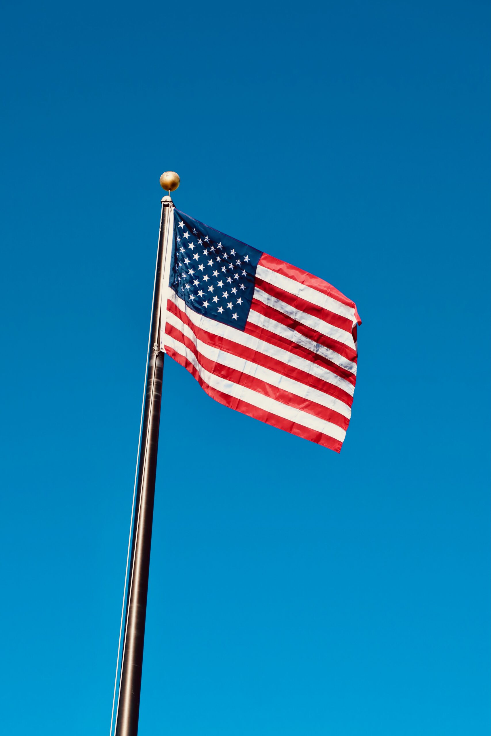 American flag waving against a clear blue sky, symbolizing the spirit of travel and freedom in the United States