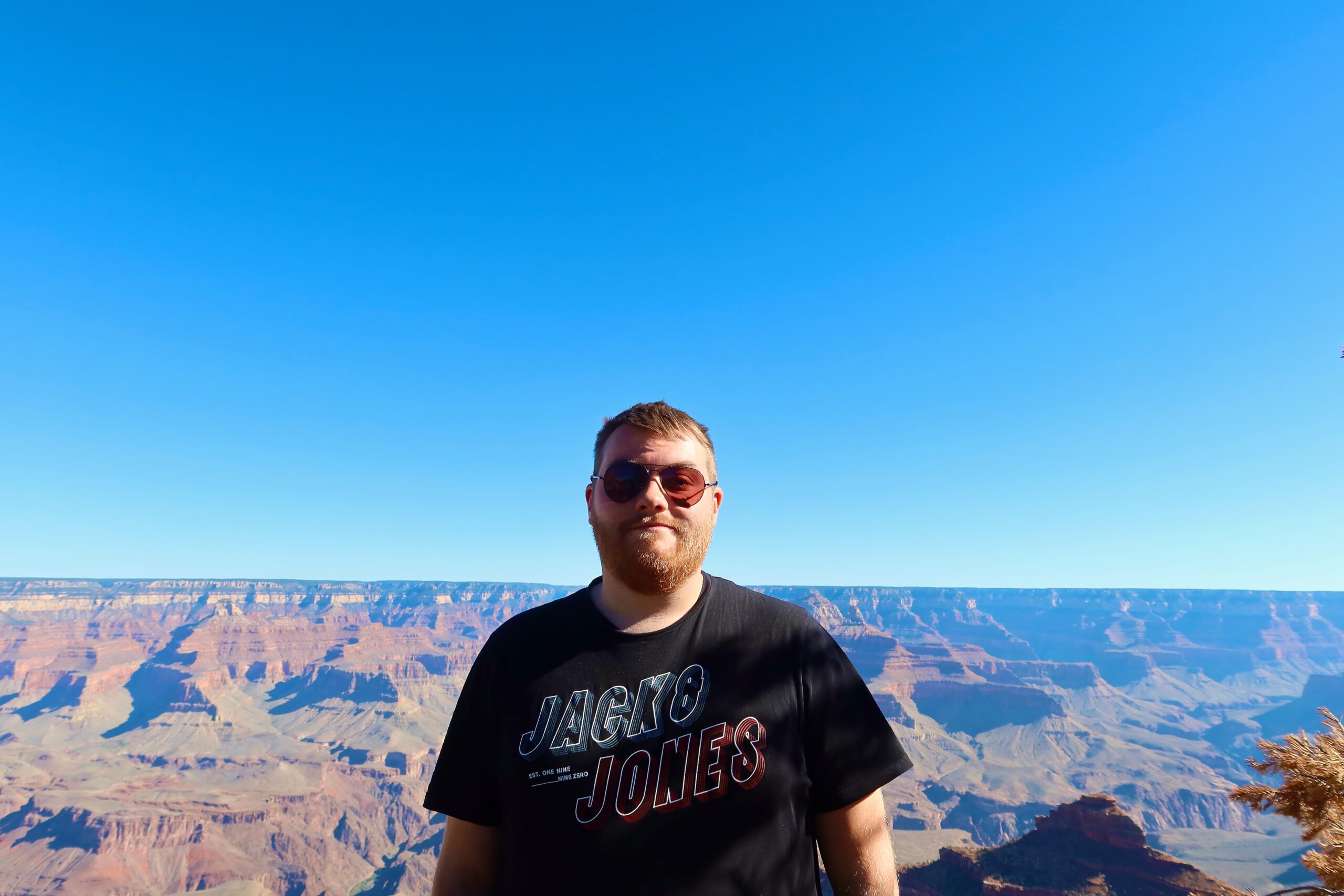Timeuw enjoying a clear view over Grand Canyon National Park from the South Rim viewpoint on a sunny day in Arizona, in a Jack & Jones shirt