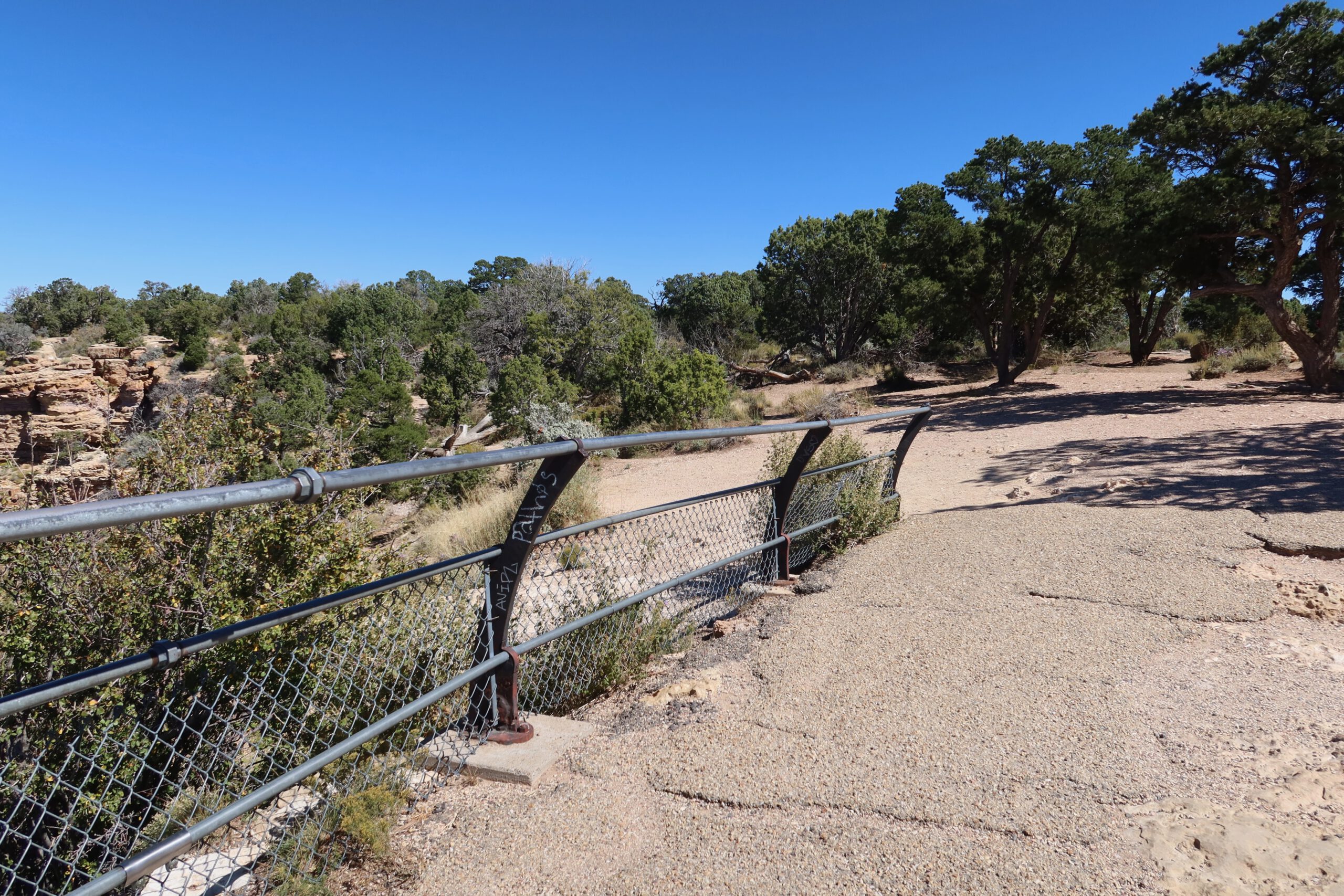 Walking path with safety railing along the rim of Grand Canyon National Park on a clear sunny day
