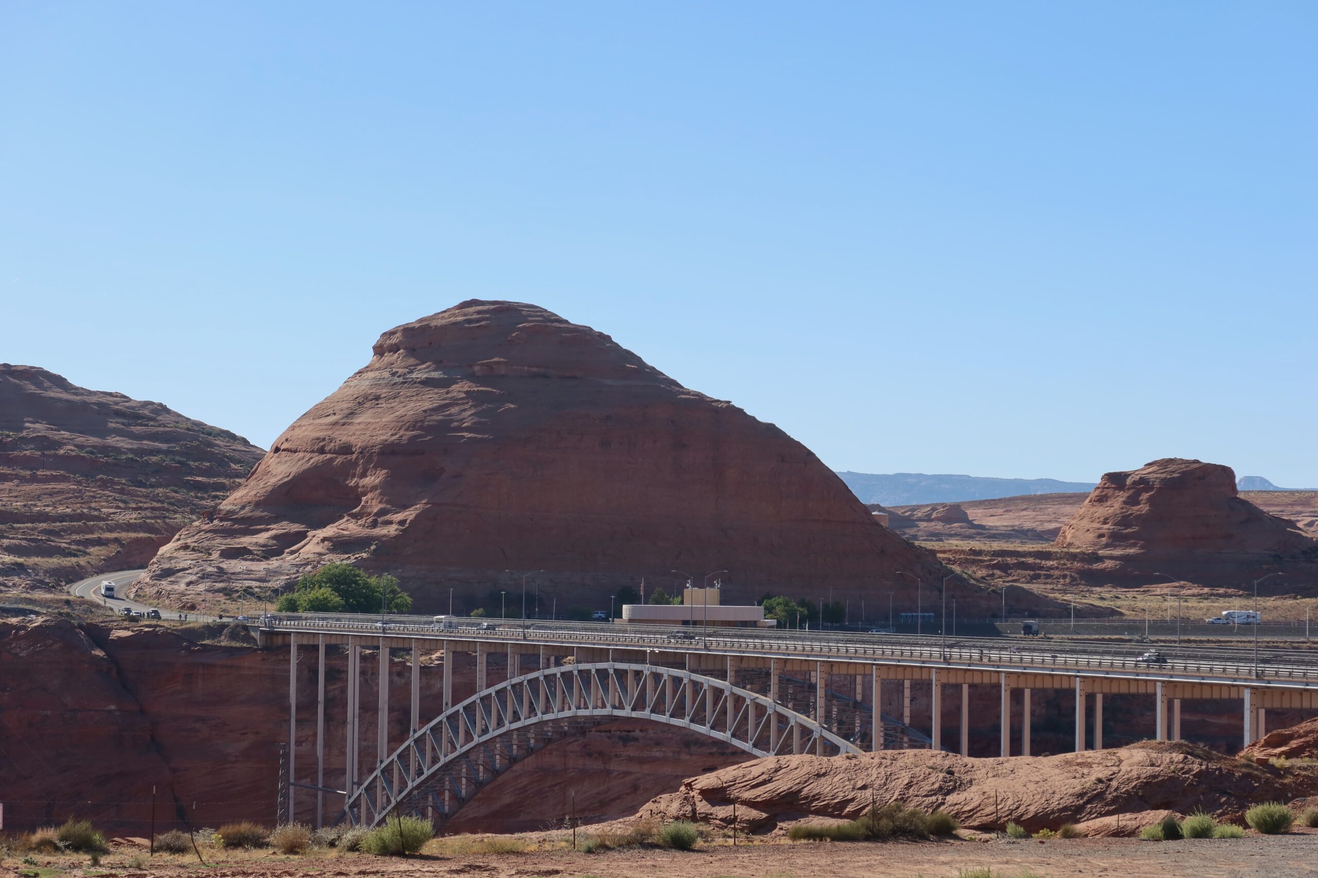 Glen Canyon Dam Bridge framed by massive red sandstone hills, iconic desert landscape and highway crossing near Page, Arizona