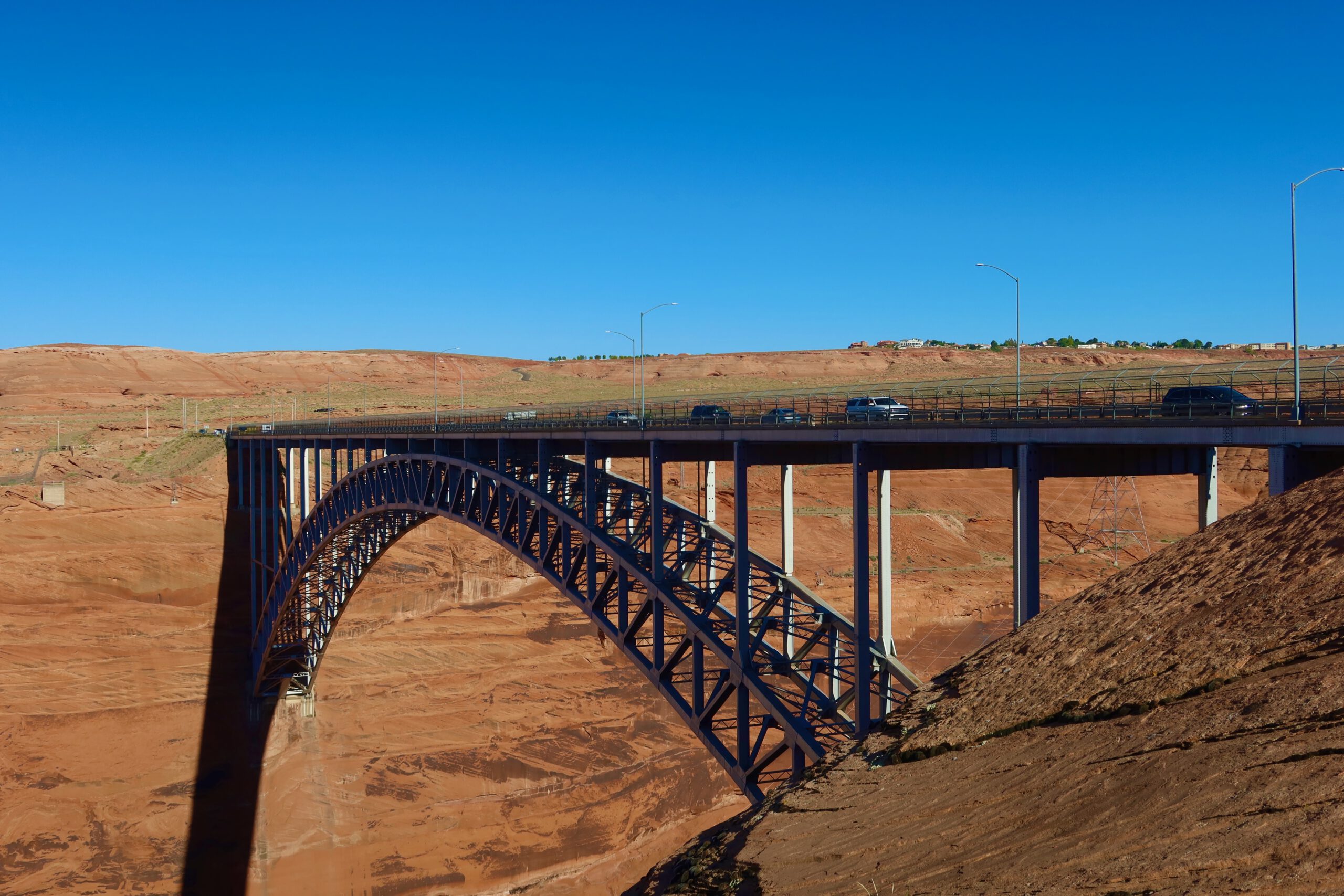 Glen Canyon Dam Bridge viewed from the side, steel arch bridge spanning a deep red rock canyon near Page, Arizona under a bright blue sky