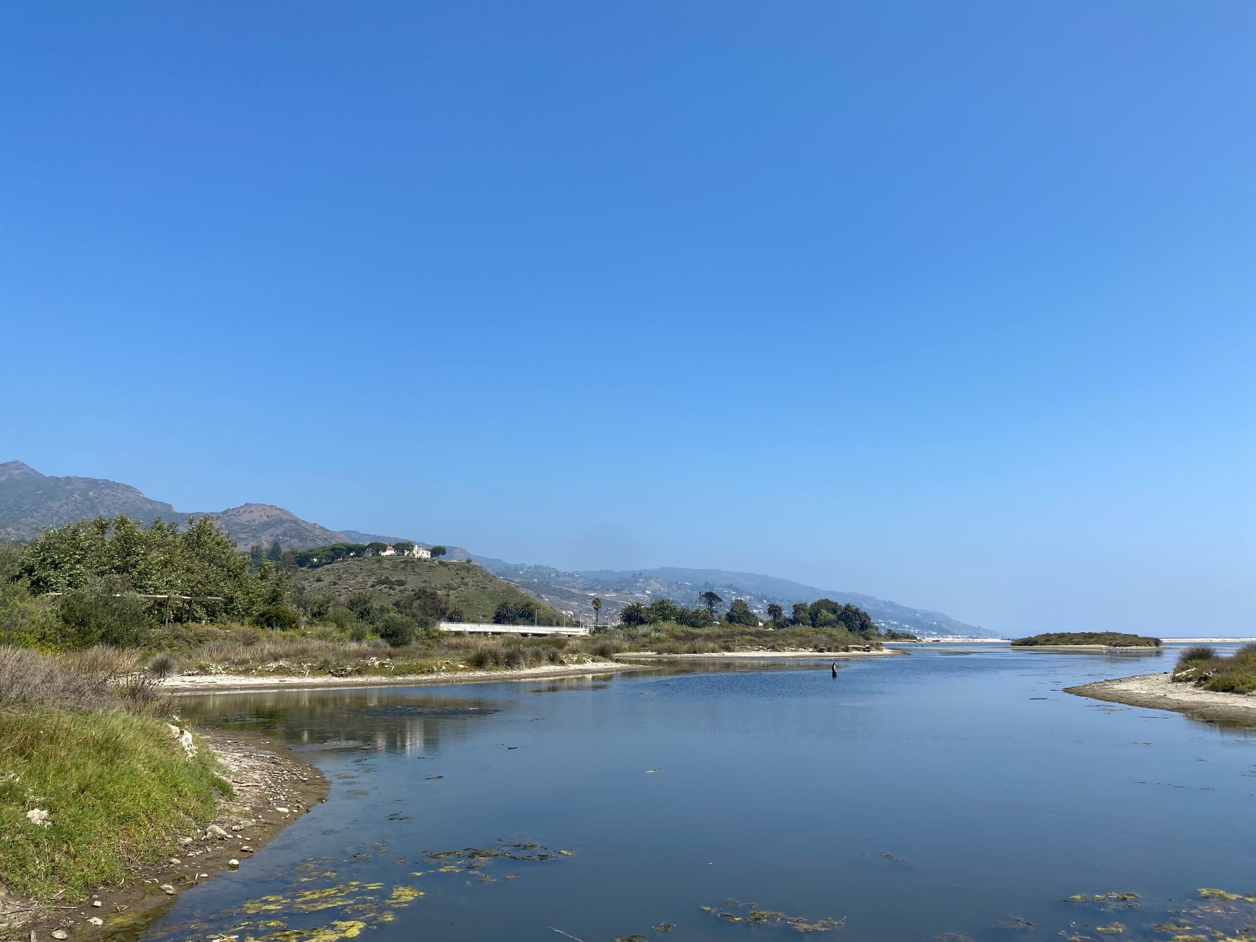 Wide view of Malibu Lagoon with reflective water, wetlands, and distant coastline