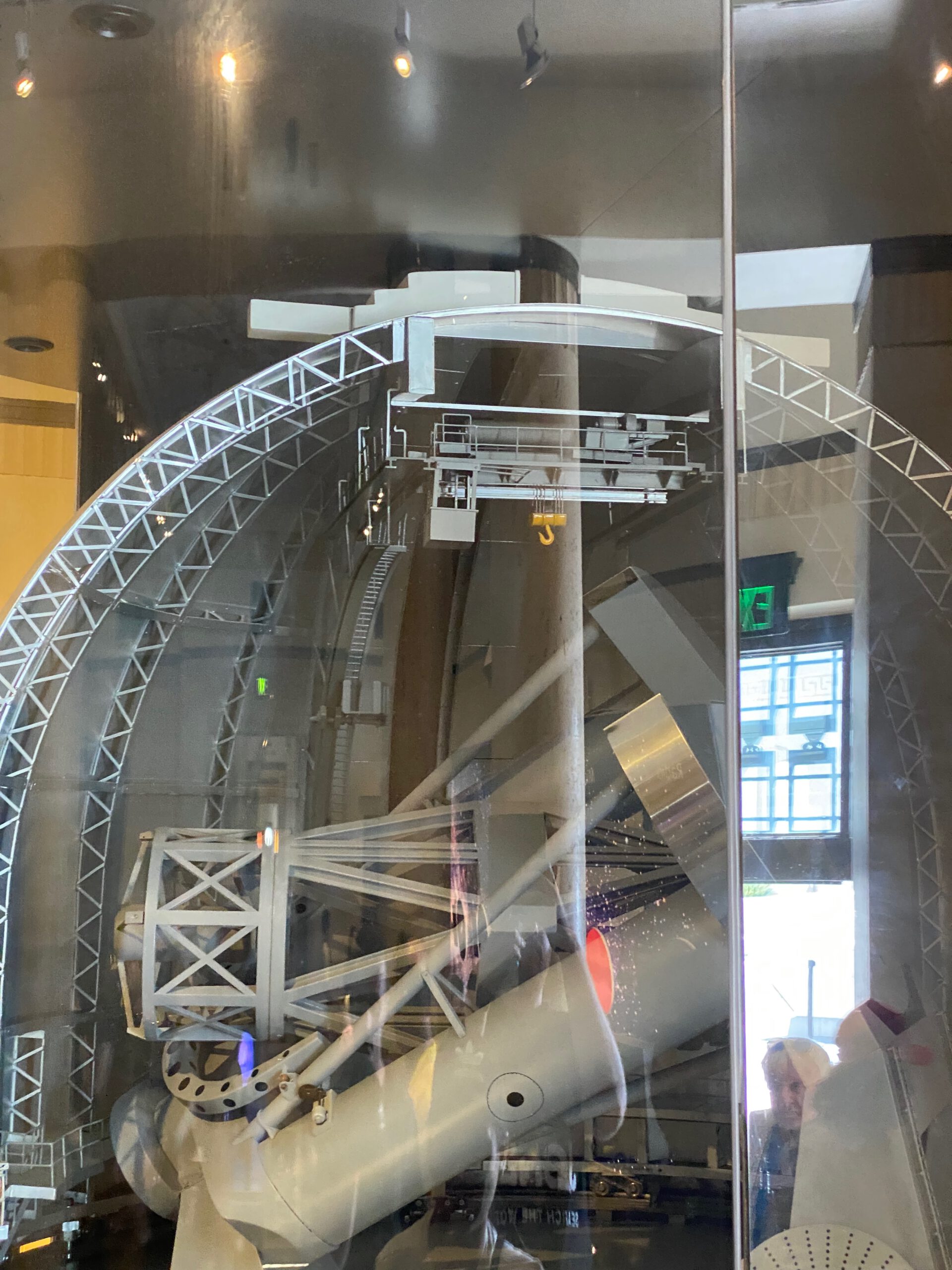 Large telescope structure and mechanical components displayed inside Griffith Observatory, illustrating historic astronomical engineering behind glass panels.